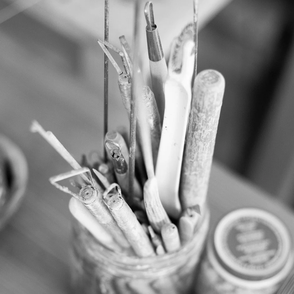 Outils de céramiste dans un pot en verre, en noir et blanc.
