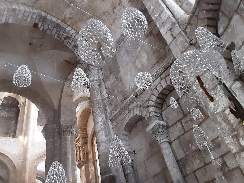 Décor d'installations d'art en verre dentelé transparent suspendues au plafond d'un bâtiment en pierre avec des arches