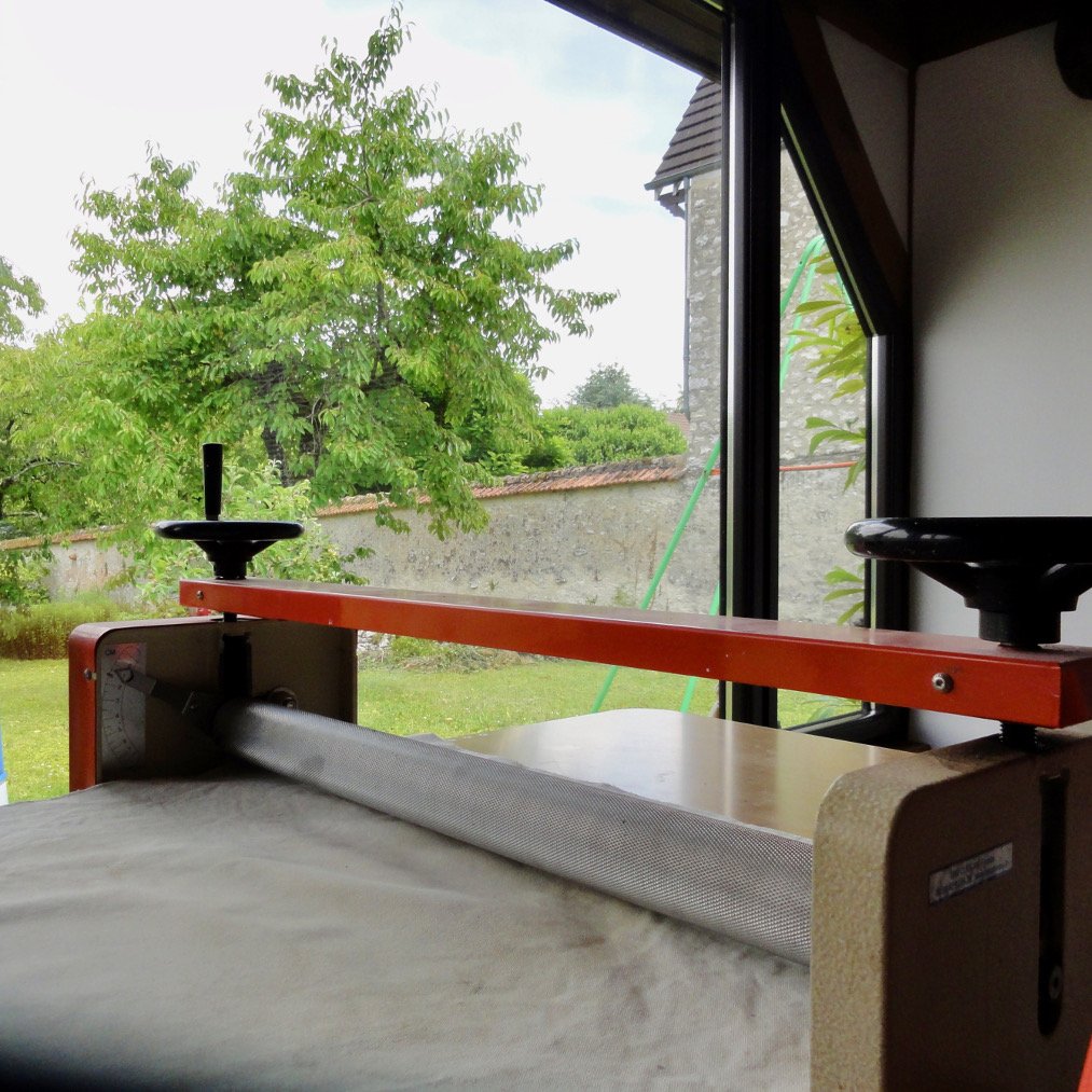 Une crouteuse pour le travail de l'argile dans un atelier avec vue sur un jardin verdoyant.