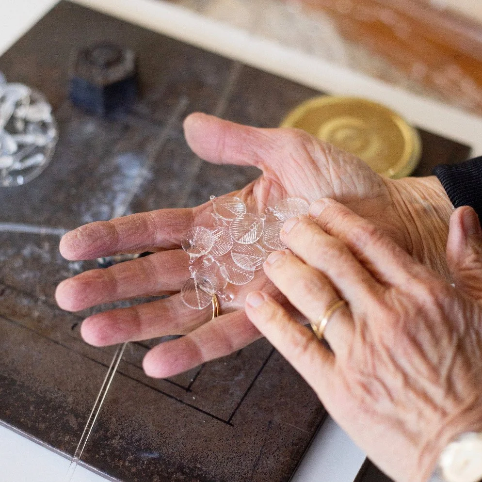 Une personne manipule du verre en forme de feuilles.
