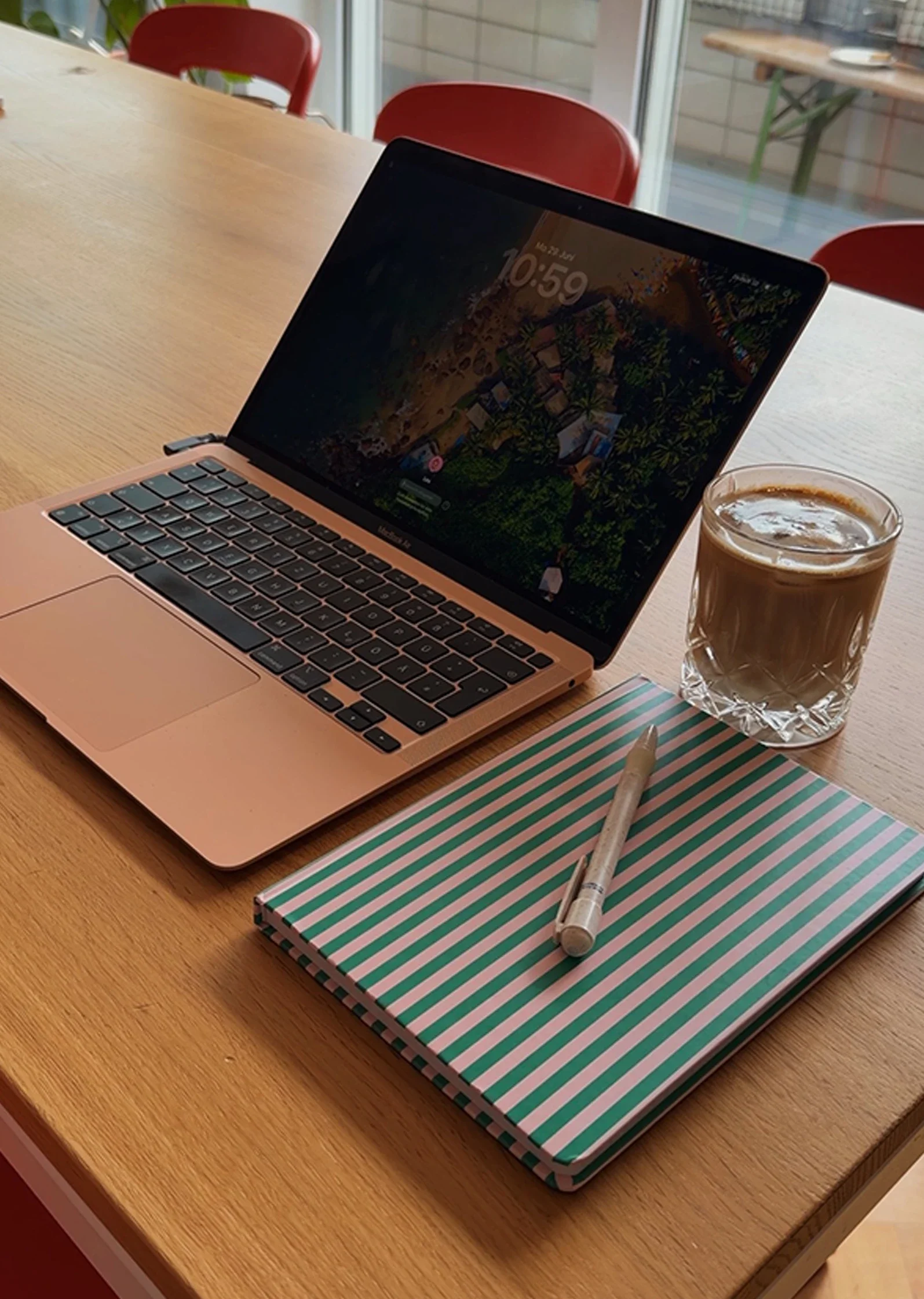 Ein Laptop, ein Notizbuch und ein Kaffee stehen auf einem Holztisch.