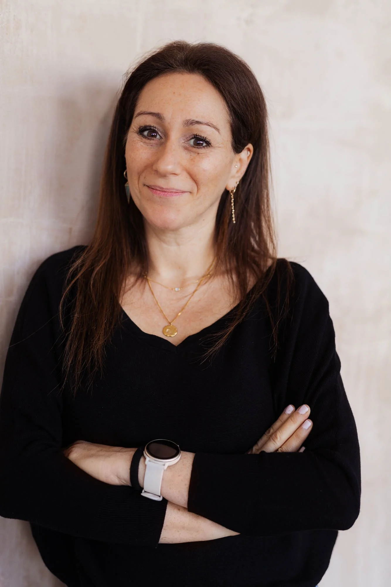 Dr Anna Colton leaning against wall with arms folded smiling at camera