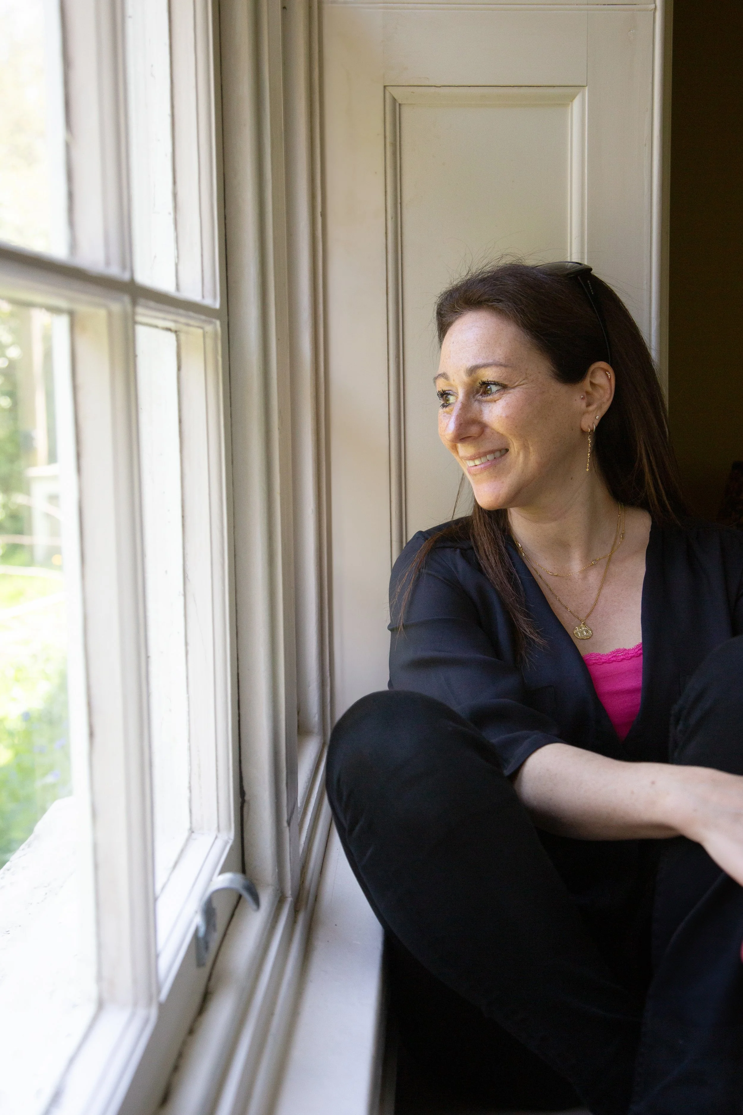 Woman sat on window seat looking out into garden