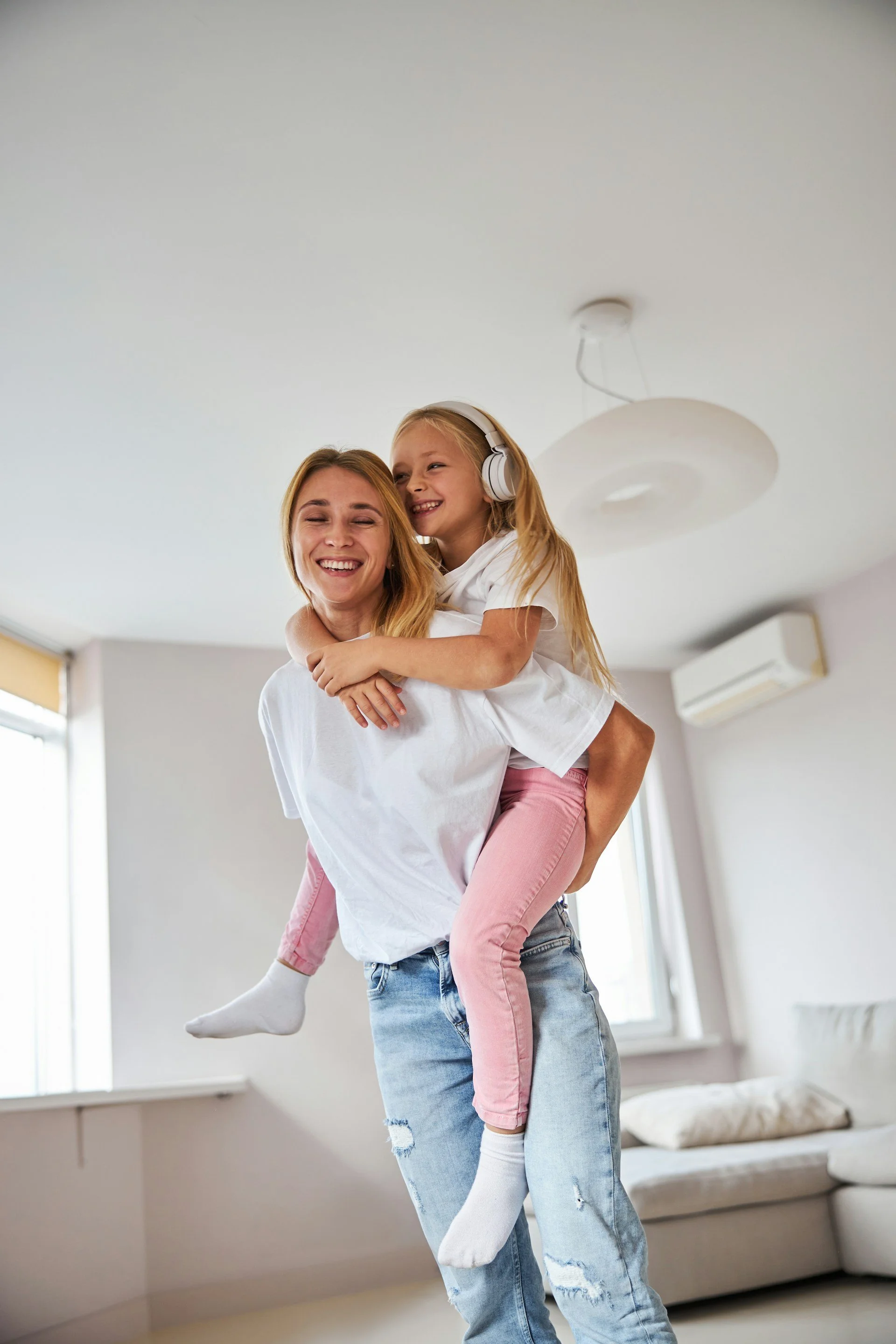 Mother standing in lounge with girl on back smiling