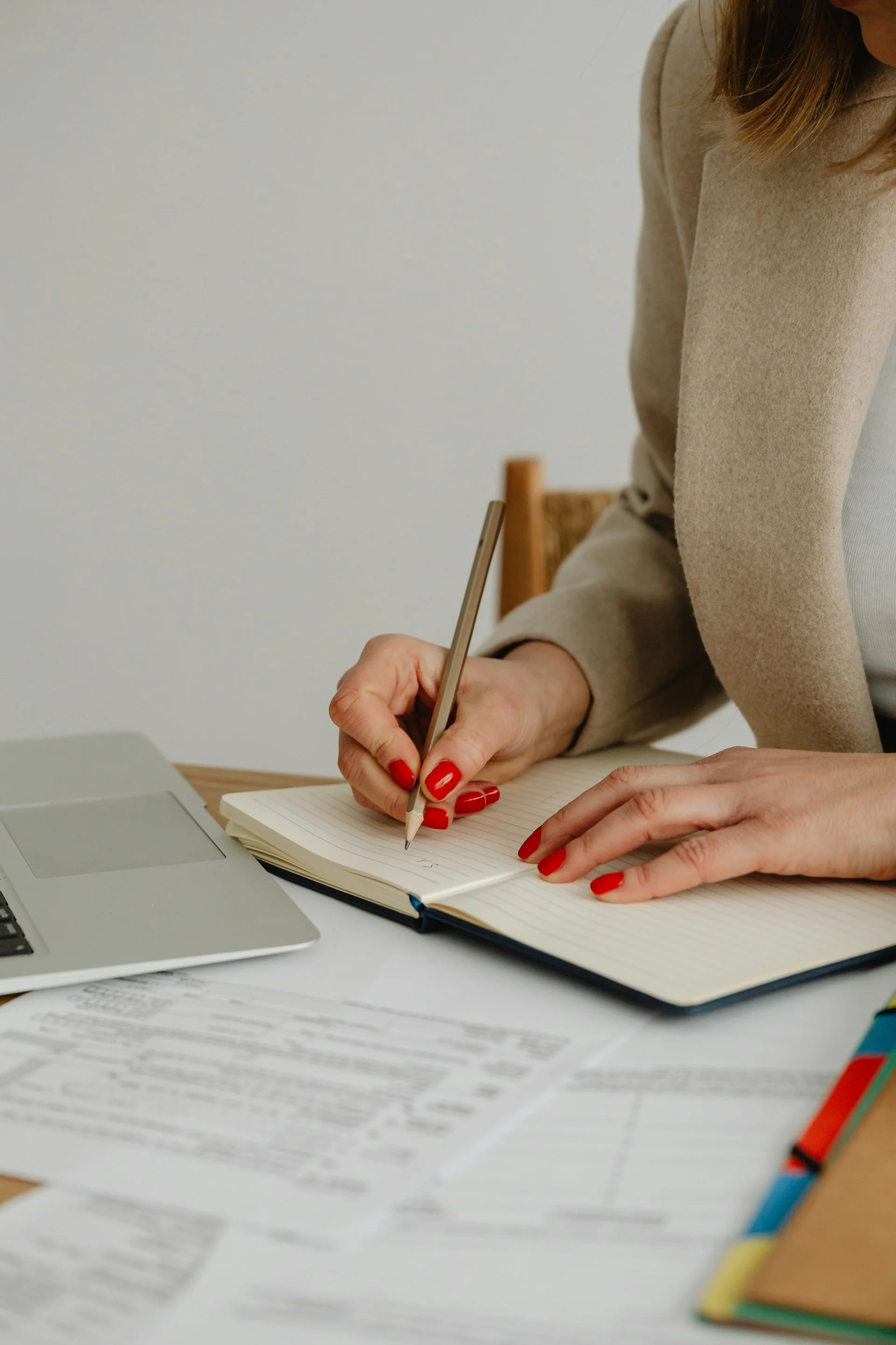 Woman with red nails writing in notebook