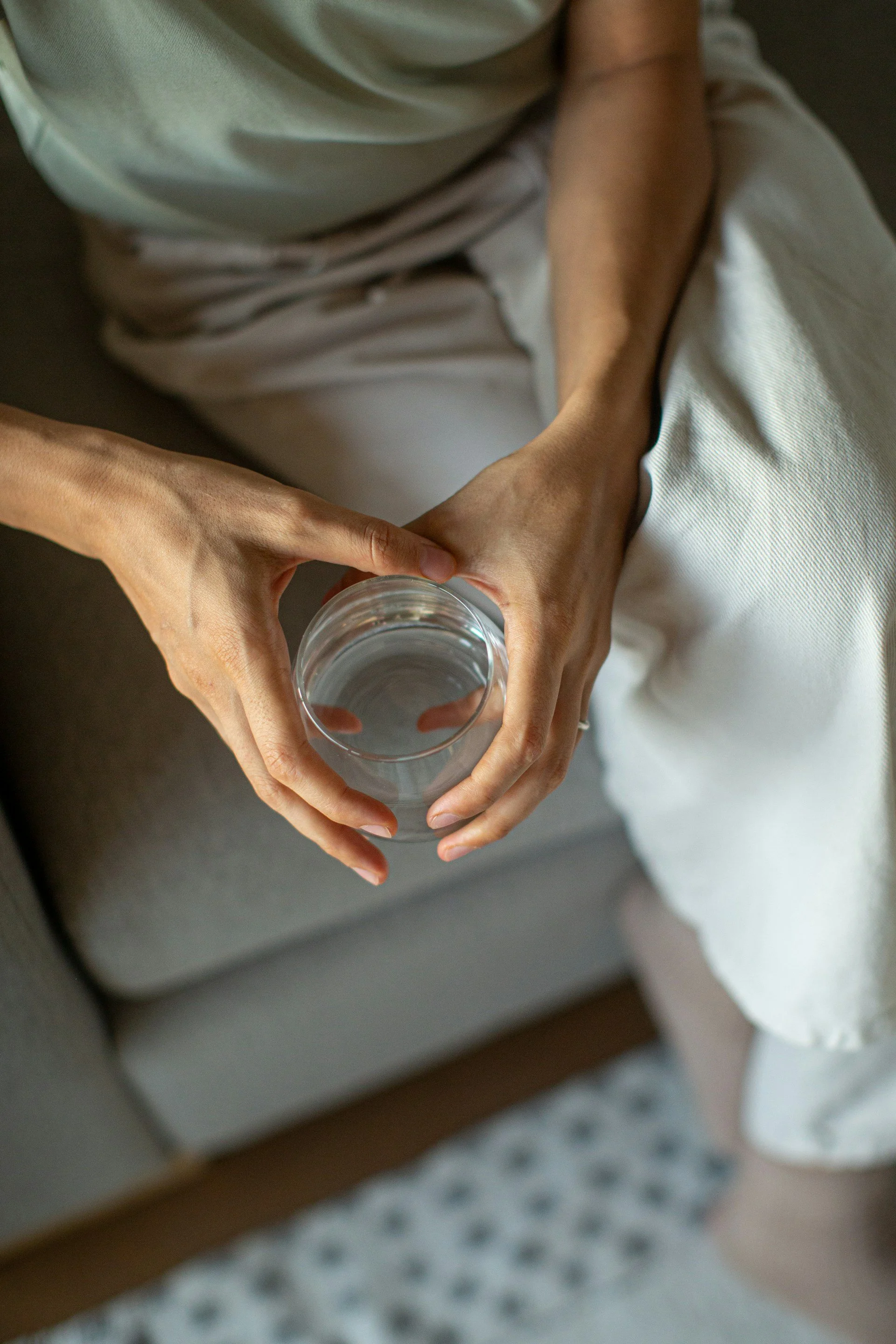 Close up of woman holding glass of water over knee