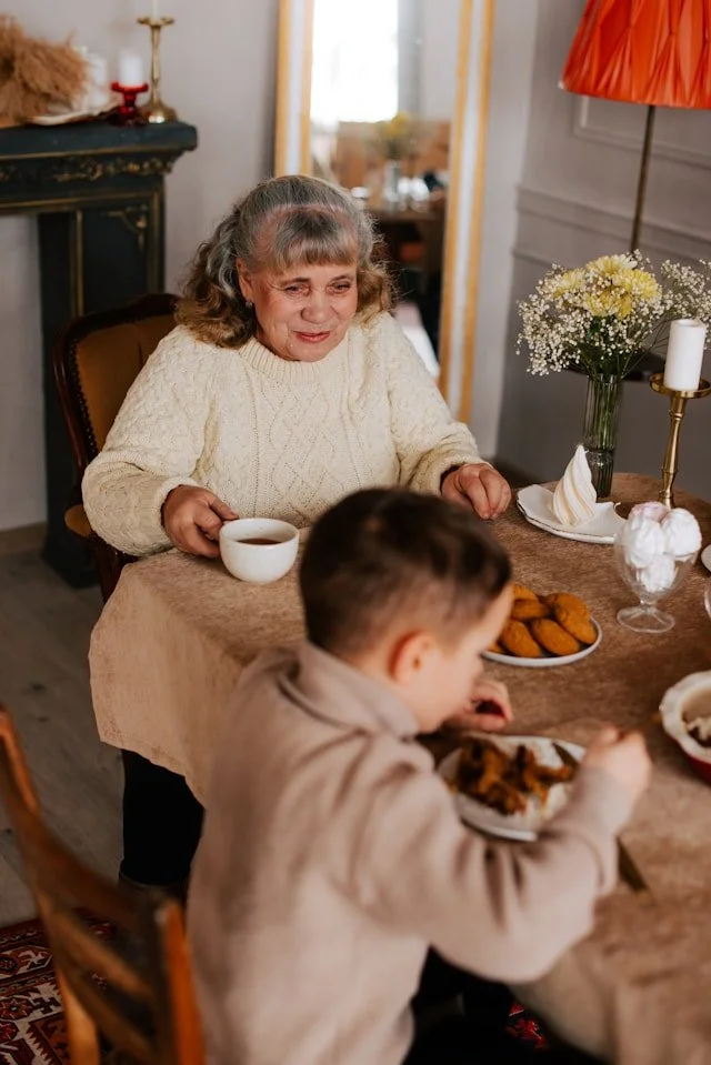 Grandparent sitting at table eating meal with Grandson