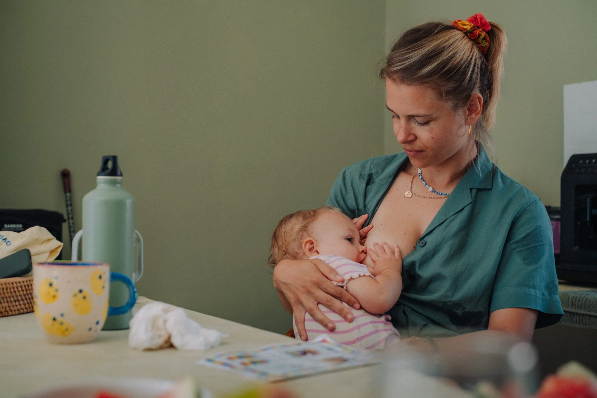 Eine Frau stillt ein Baby an ihrer Brust in einer häuslichen Umgebung.