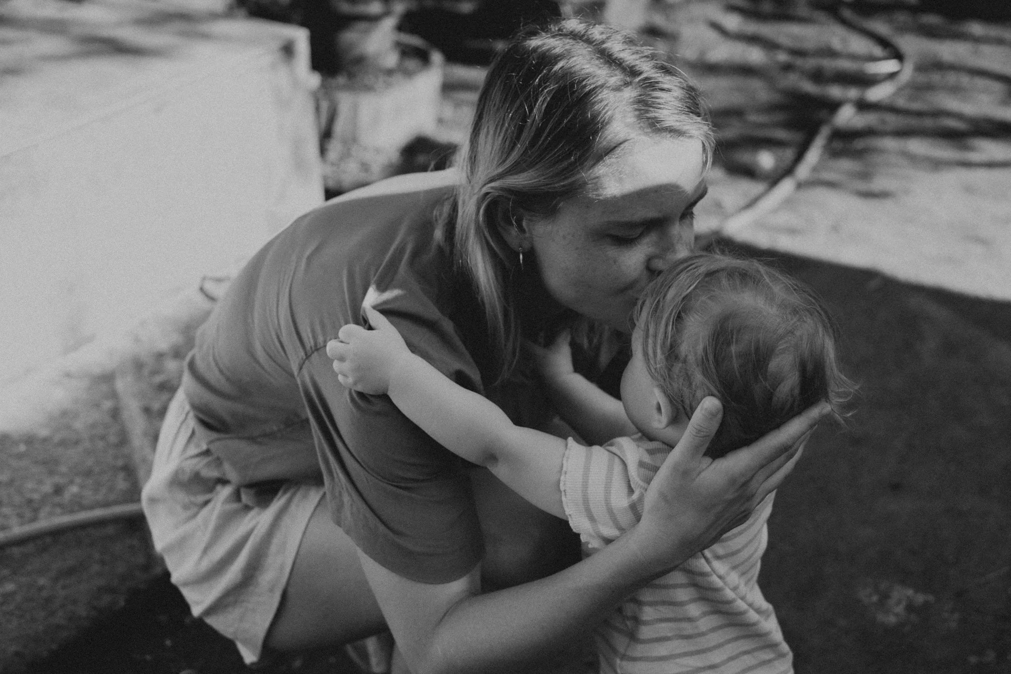 Eine Frau und ein Kind umarmen sich liebevoll, die Frau küsst das Kind auf die Stirn.