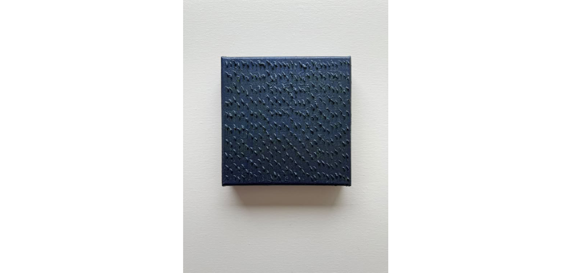 A blue textured rectangular object hanging on a white wall.