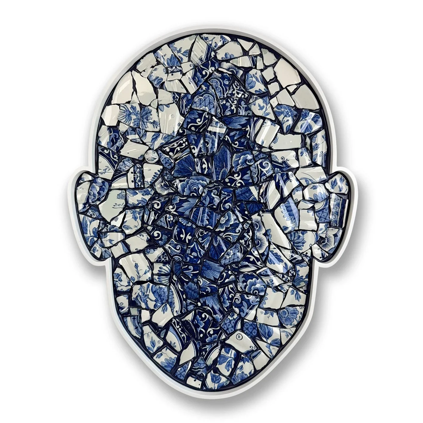 A mirror shaped like a human head, made of broken pieces of blue and white patterned ceramic tiles.