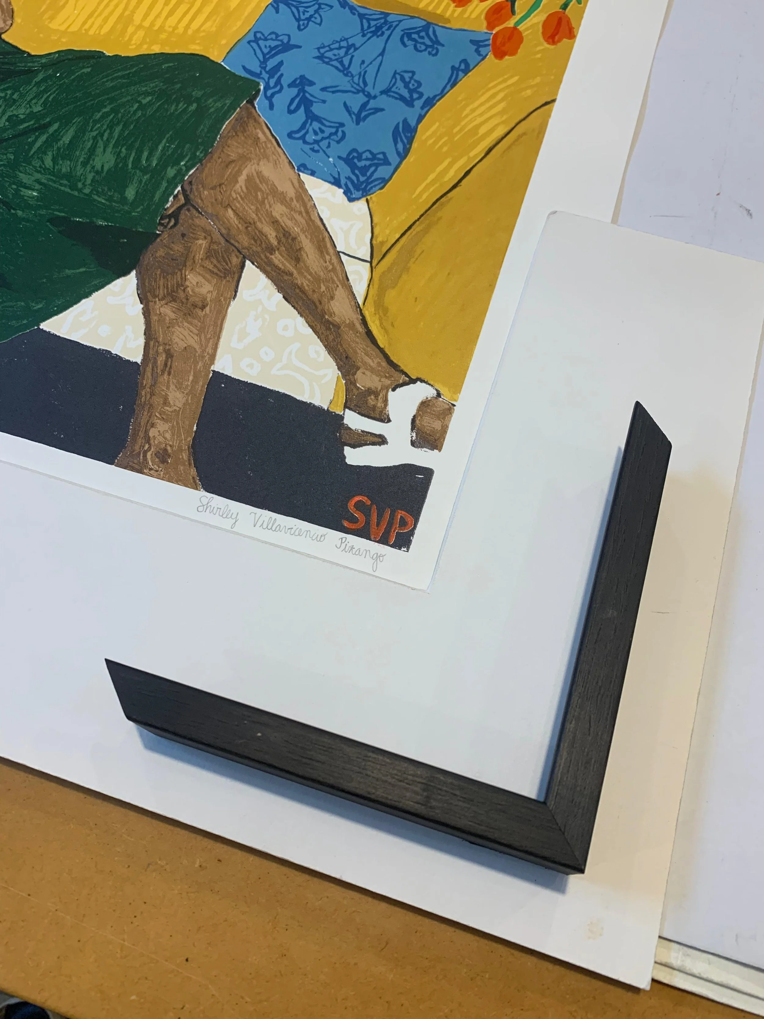 Close-up of a colorful artwork featuring a person in green shorts, a blue shirt, and yellow pants, with the signature 'Shirley Villarrione Piranho' and the initials 'SVP' in red in the bottom corner.