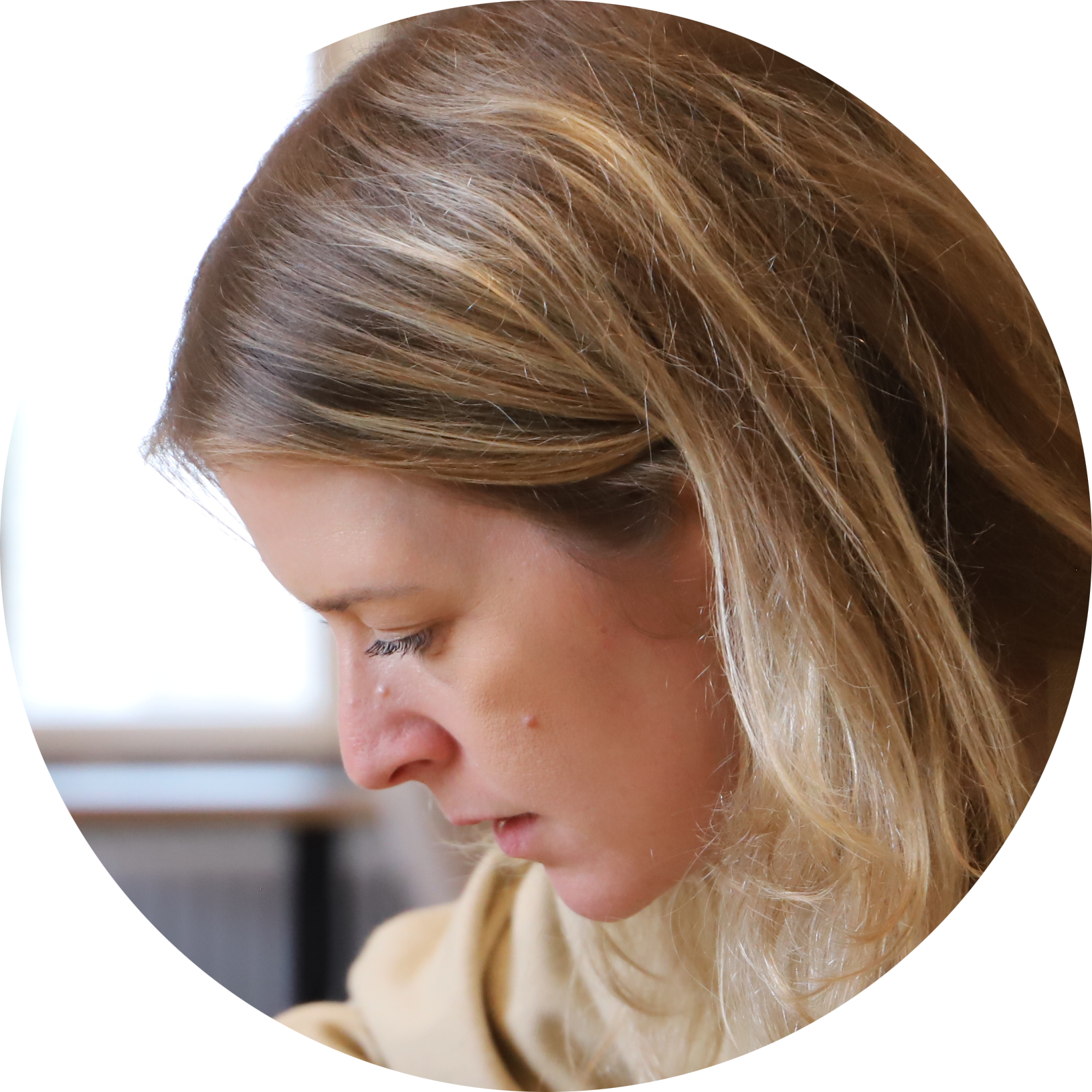 A woman with light brown hair, looking downwards, with a focused expression.