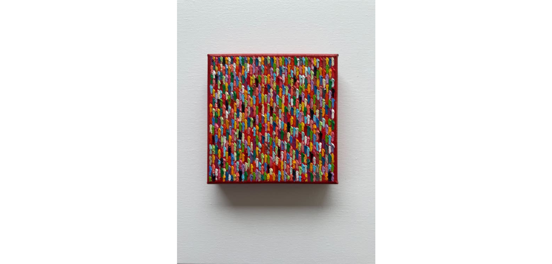 Colorful abstract artwork with numerous small, multicolored threads or brushstrokes arranged on a red background, framed in red.