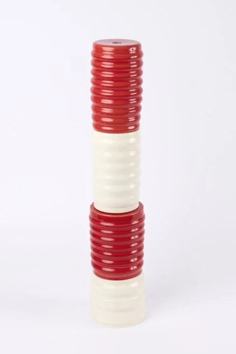 Stacked plastic discs in red and white colors, alternating and arranged vertically.
