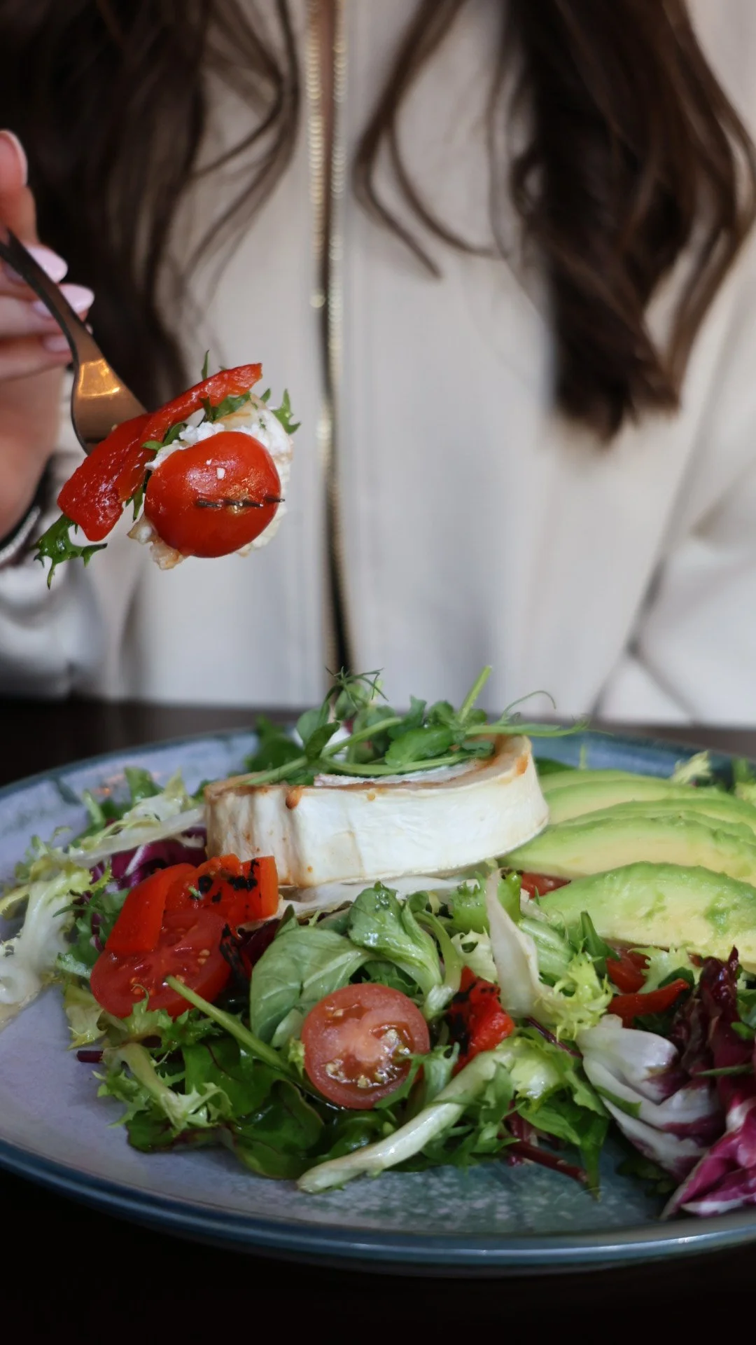 Various plates of gourmet food including salads, bread, and desserts arranged on a wooden table, with drinks.