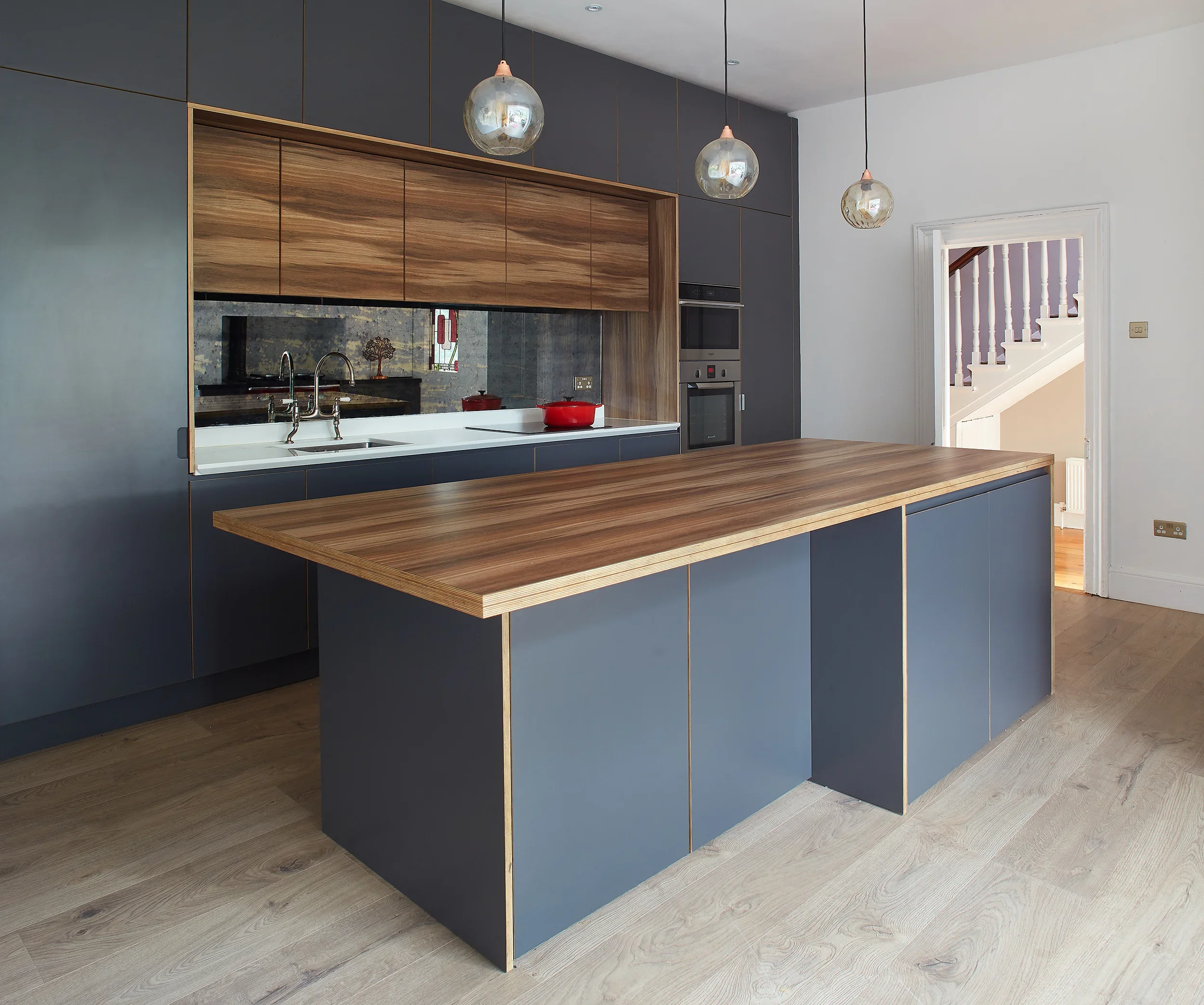 Contemporary open-plan kitchen featuring matte Anthracite Grey handleless cabinetry with exposed birch plywood edges, built-up birch ply kitchen island work surface with breakfast bar seating, built-in Knockrea pantry unit.