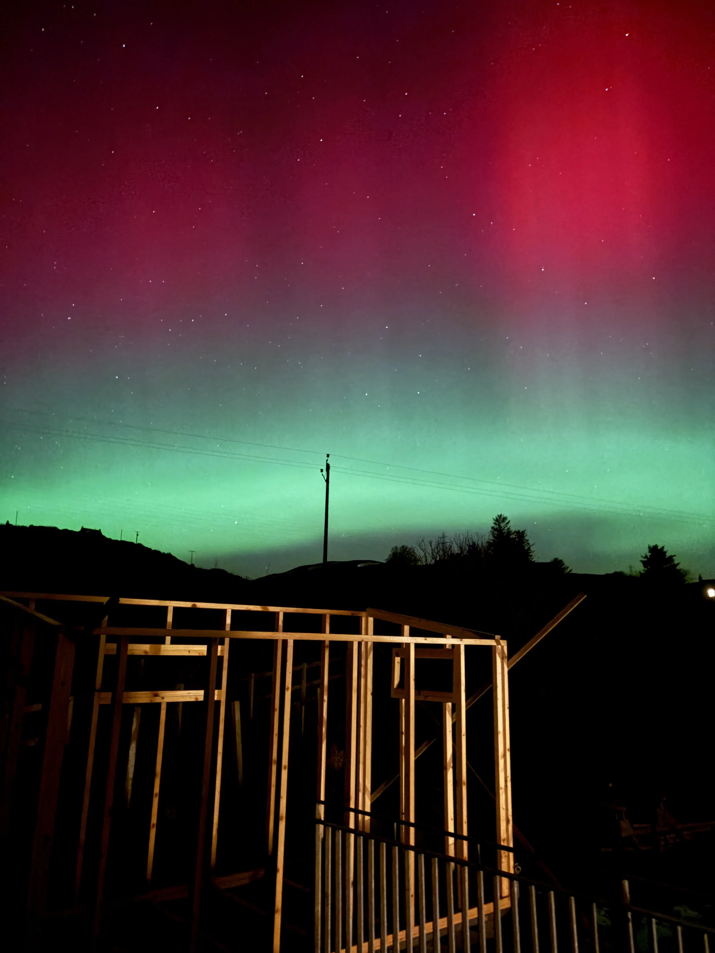 Mountain landscape with snow-capped peaks in the background and a modern building on green rolling hills in the foreground.