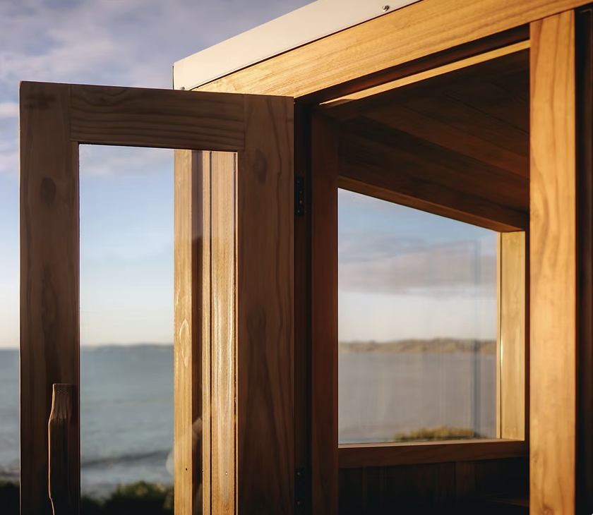 Close-up view of a wooden window frame with glass, overlooking a body of water and distant land.