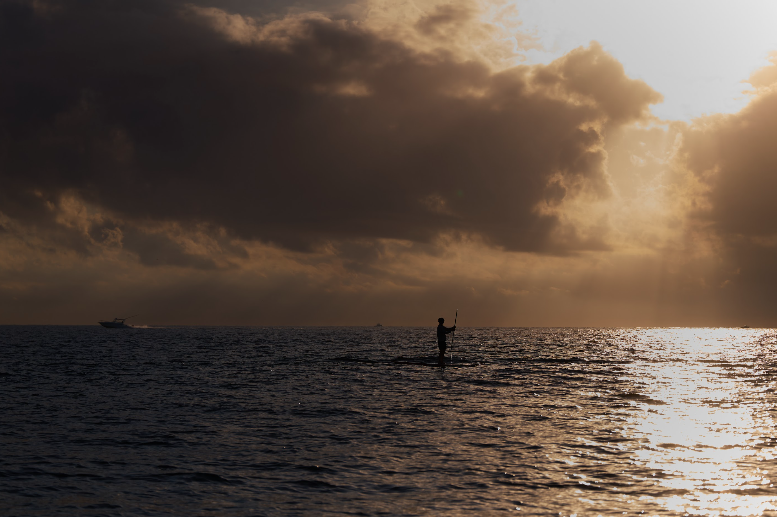  Landscape of gray skies in the horizon over water during sunset with a paddle boarder going out. 