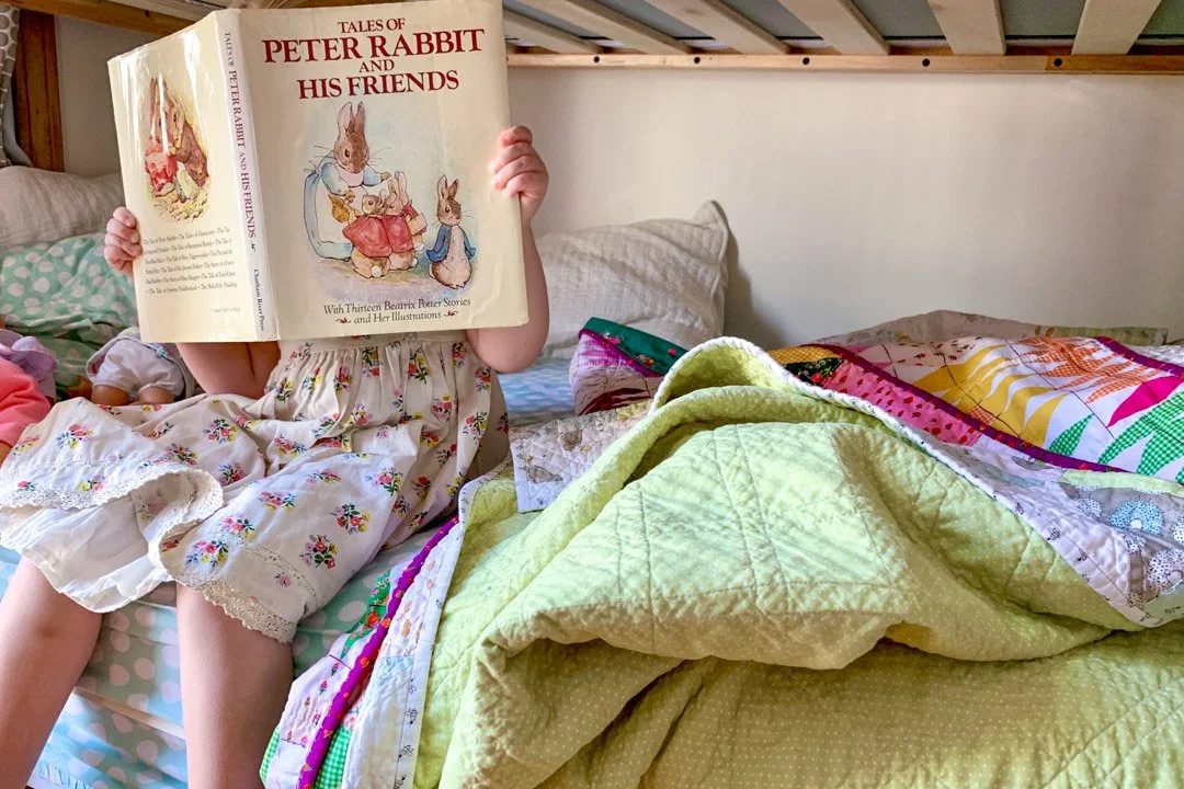 child reading Peter Rabbit on a lower bunk bed