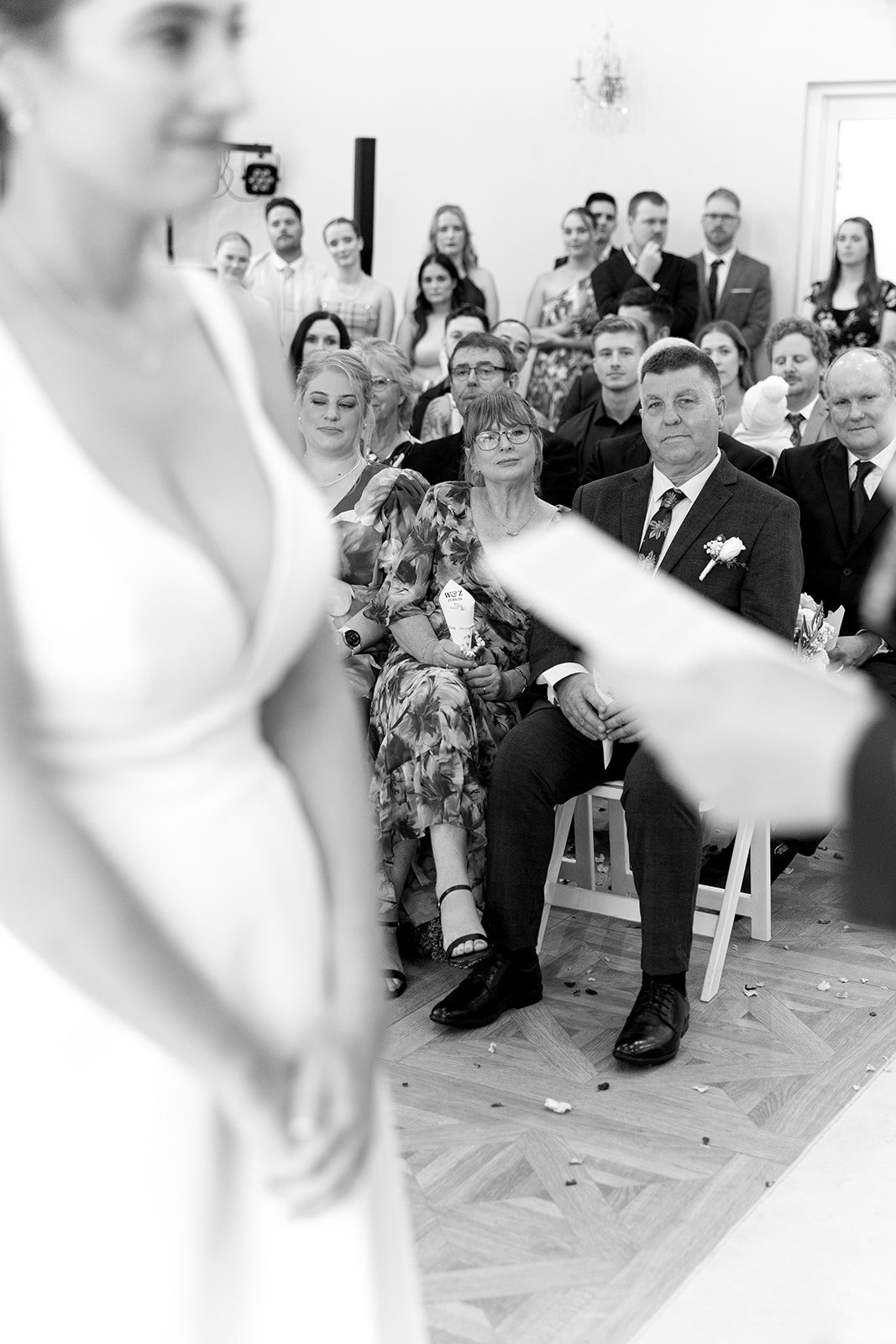 Black and white photo of a wedding ceremony with guests seated and watching the bride and groom.