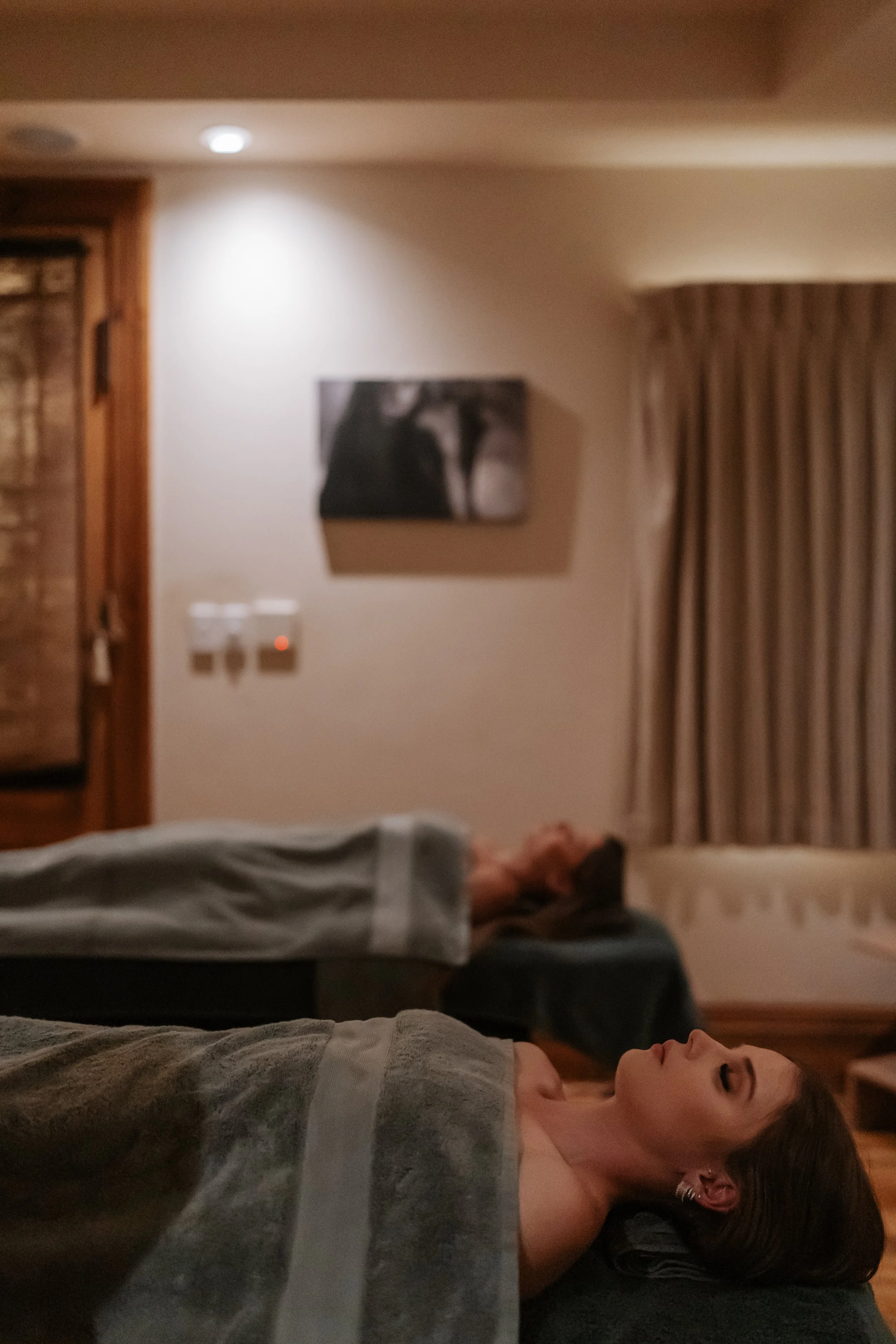 Women lying on massage tables in a dimly lit room, relaxing.