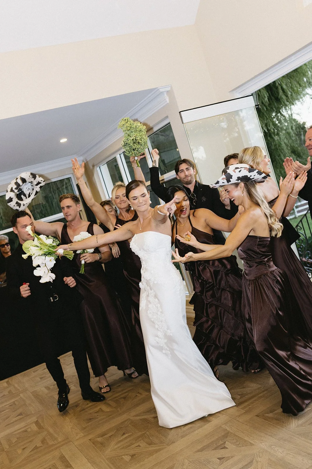 A bride and her bridesmaids celebrating at a wedding reception, dancing and having fun indoors.