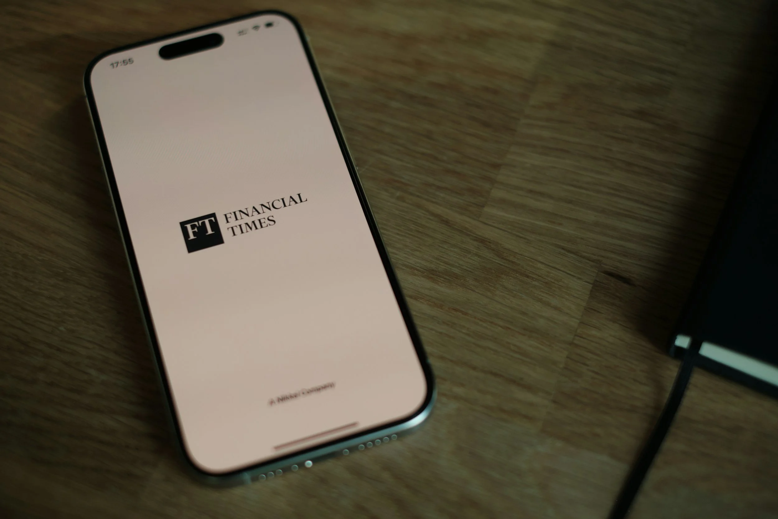 Smartphone displaying the Financial Times logo on a wooden surface.