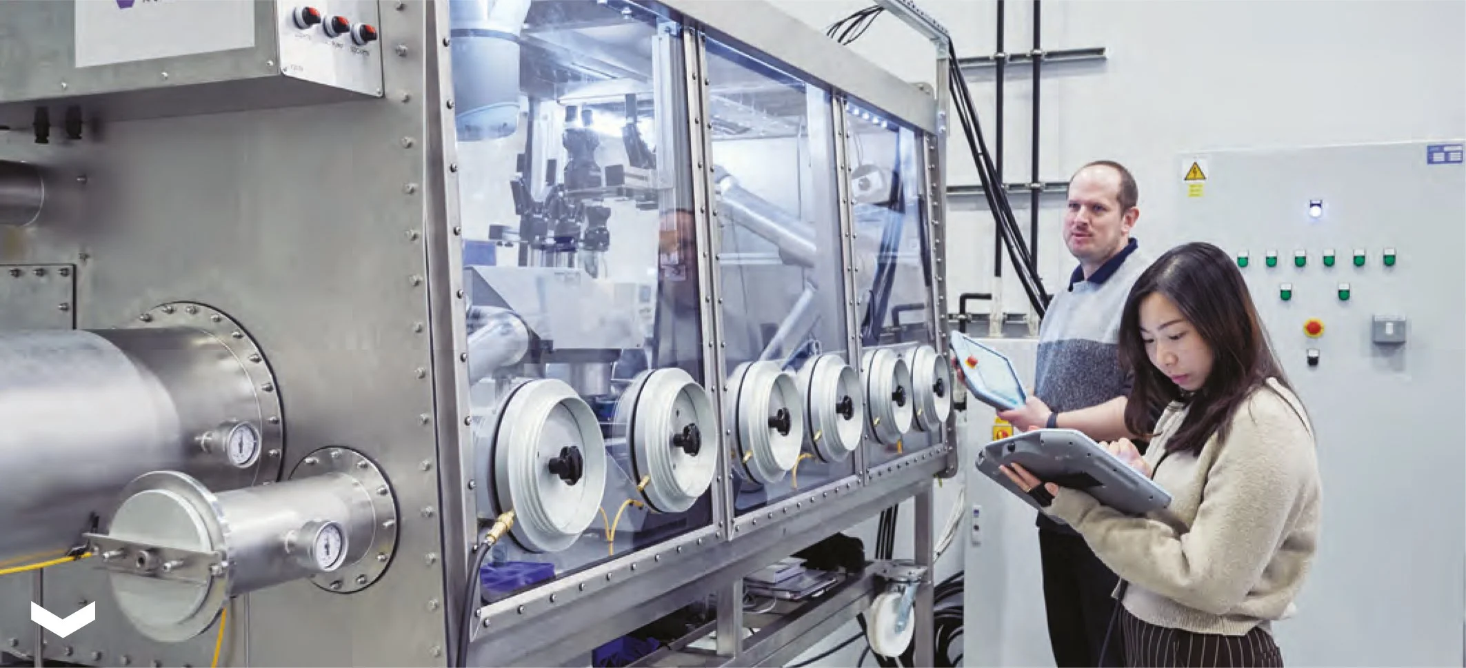 A robot dog with a camera head on four legs is in a laboratory environment, with a computer monitor displaying an image of the robot dog in the foreground.
