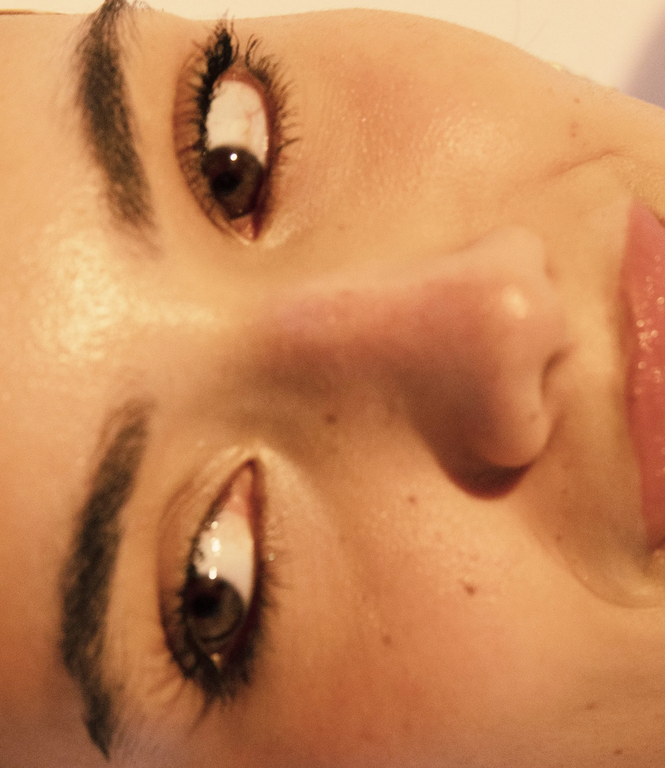 Close-up of a woman's face lying on her side with makeup, eyes open, and a neutral expression.