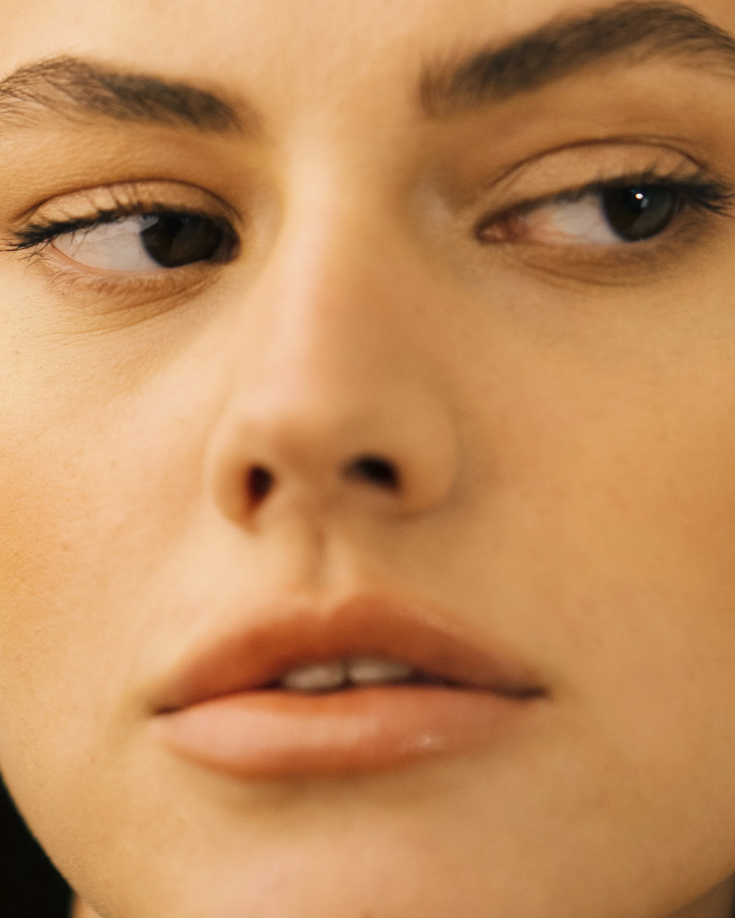 Close-up of a person's face showing only part of their eyes, nose, and lips with a natural complexion.