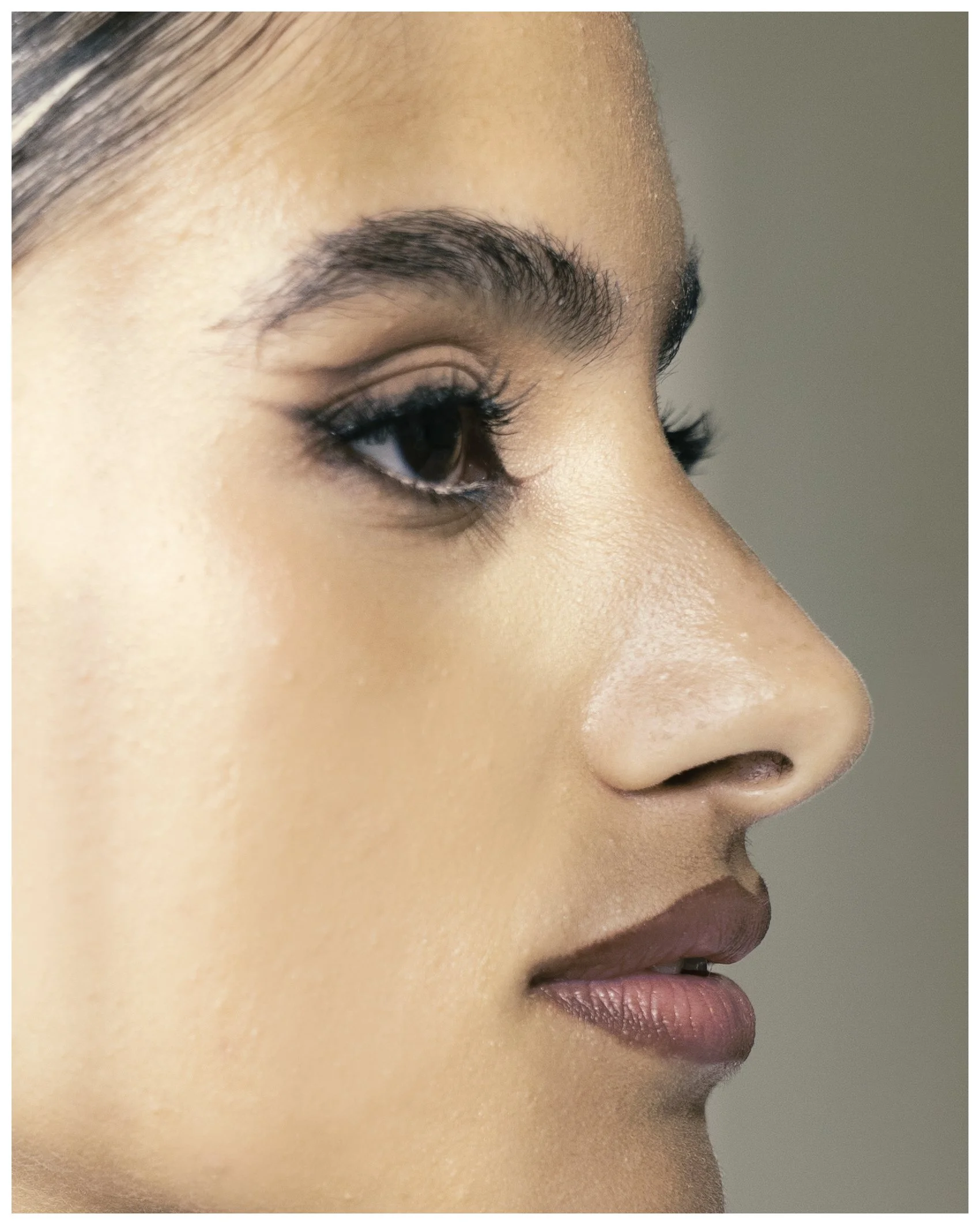 Close-up side profile of a woman with smooth skin, dark eye makeup, and natural lips.