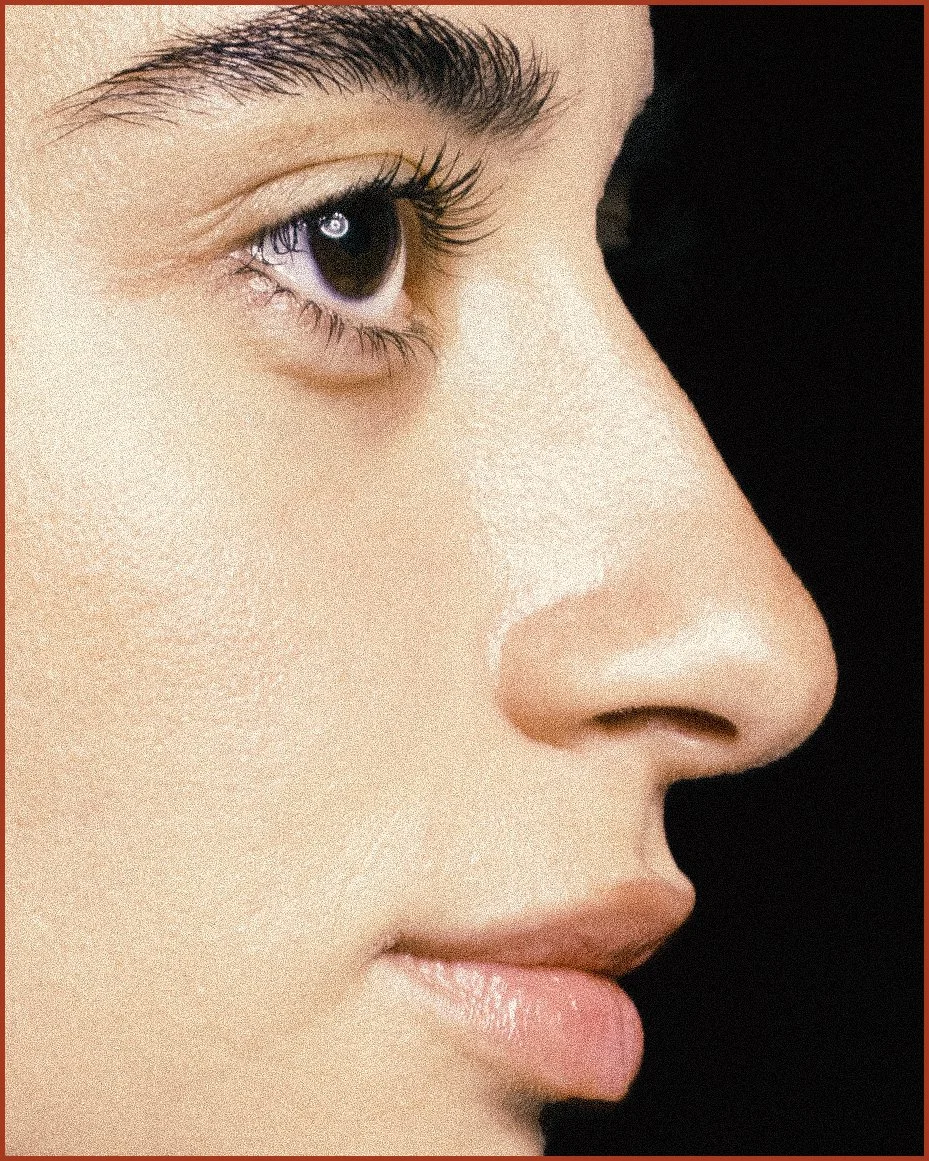Close-up side profile of a woman's face, showing her eye, nose, and lips against a black background.