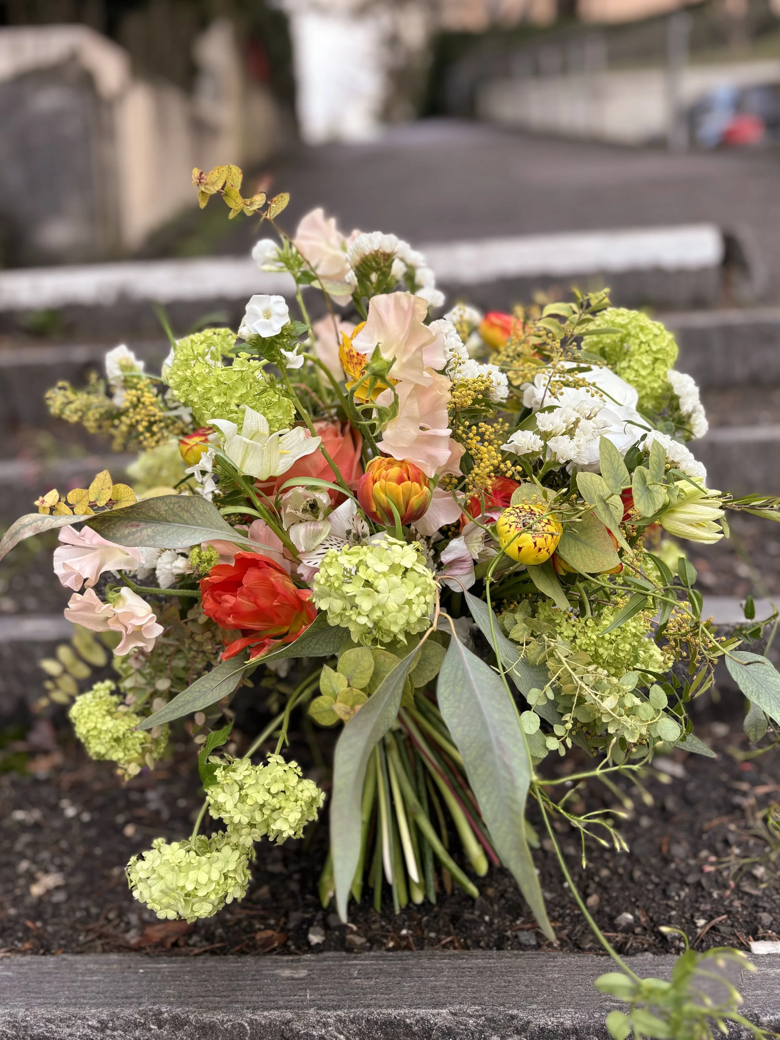 Blumenstrauß mit verschiedenen bunten Blumen, liegt auf einer Bank im Freien