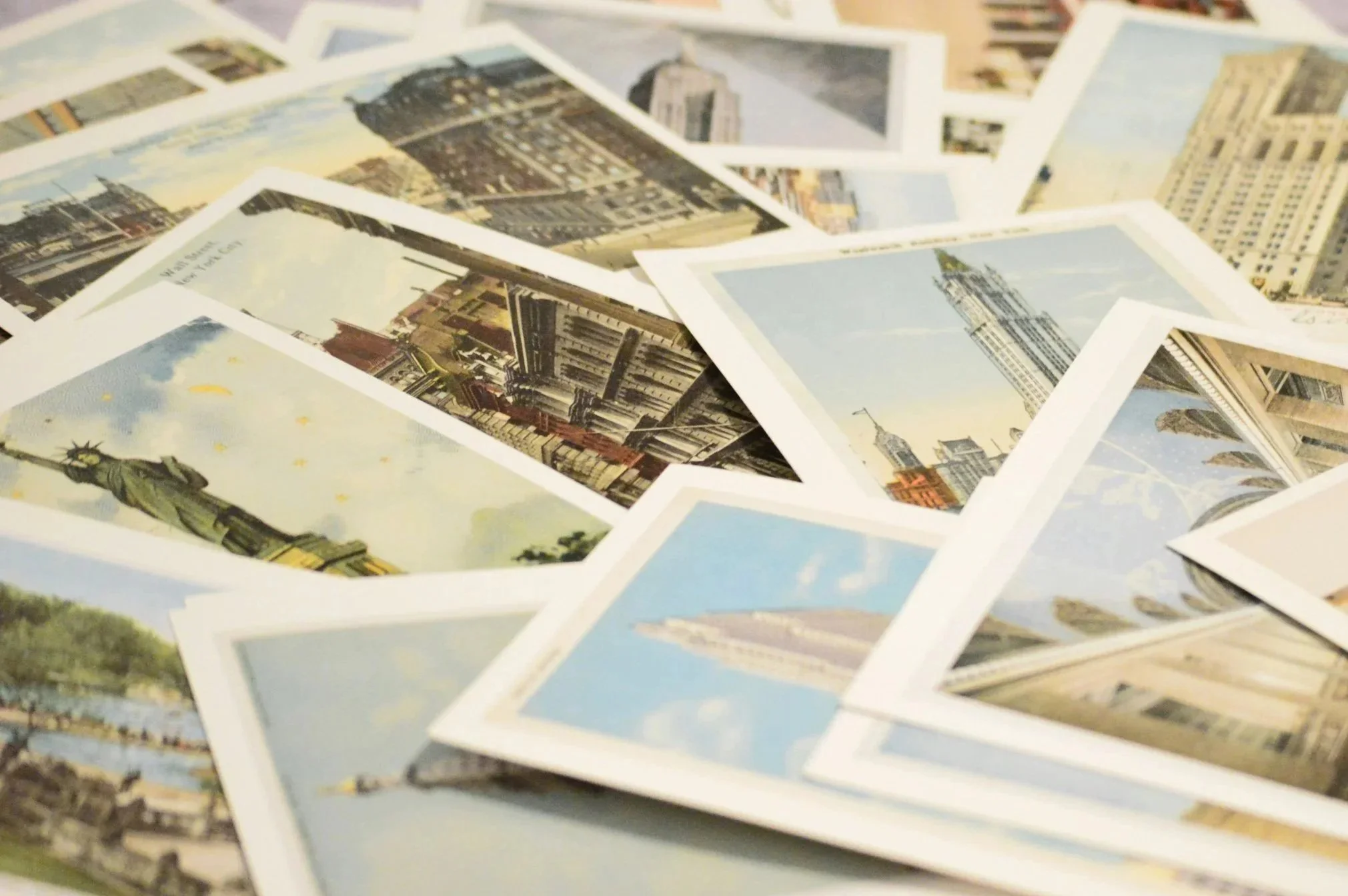 A pile of various printed photographs, including images of cityscapes and landmarks such as the Statue of Liberty and tall buildings.