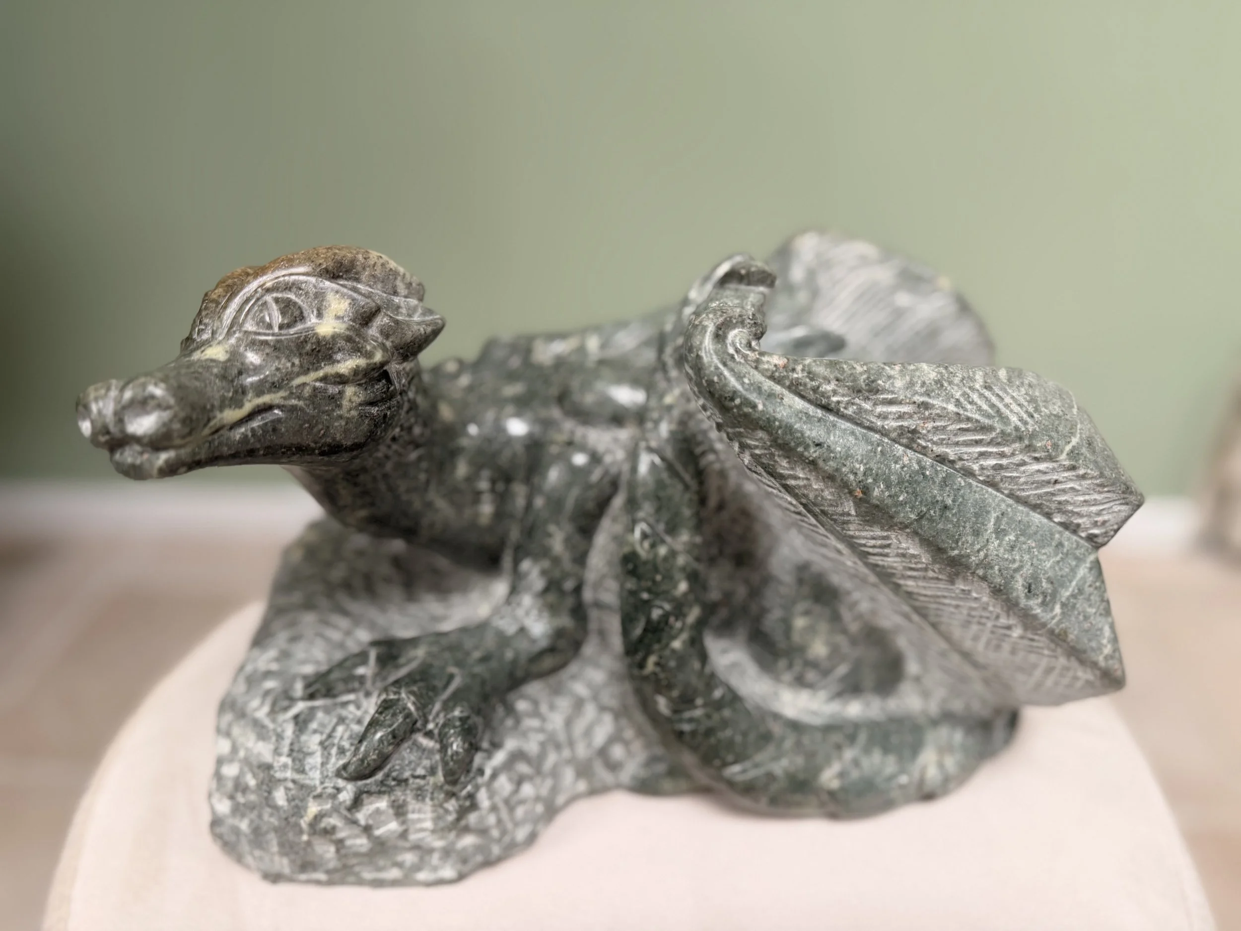 Steinfigur eines erwachten Drachen, der beginnt, seine Flügel auszubreiten.