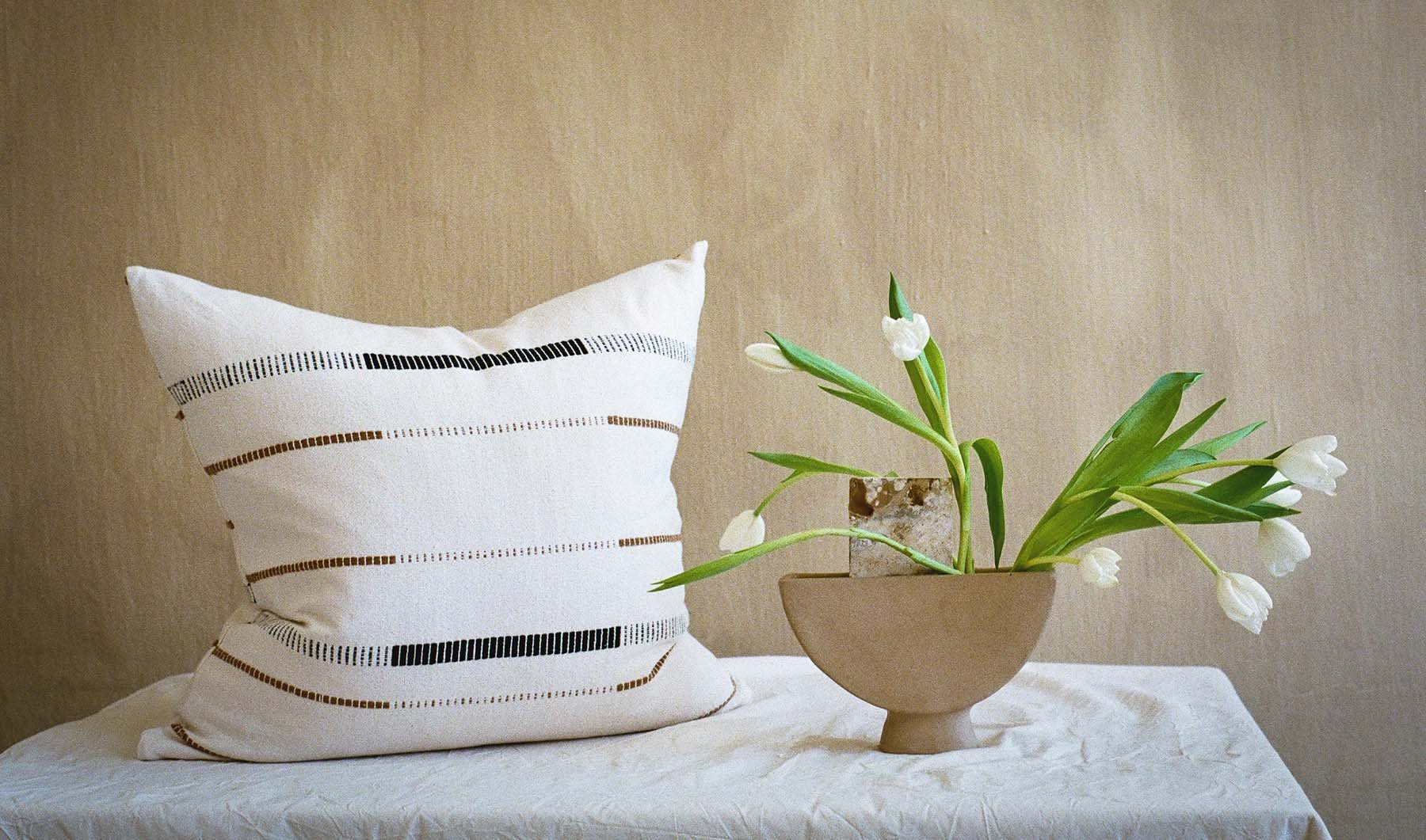 An image of the fulcrum cushion next to a vase with tulips