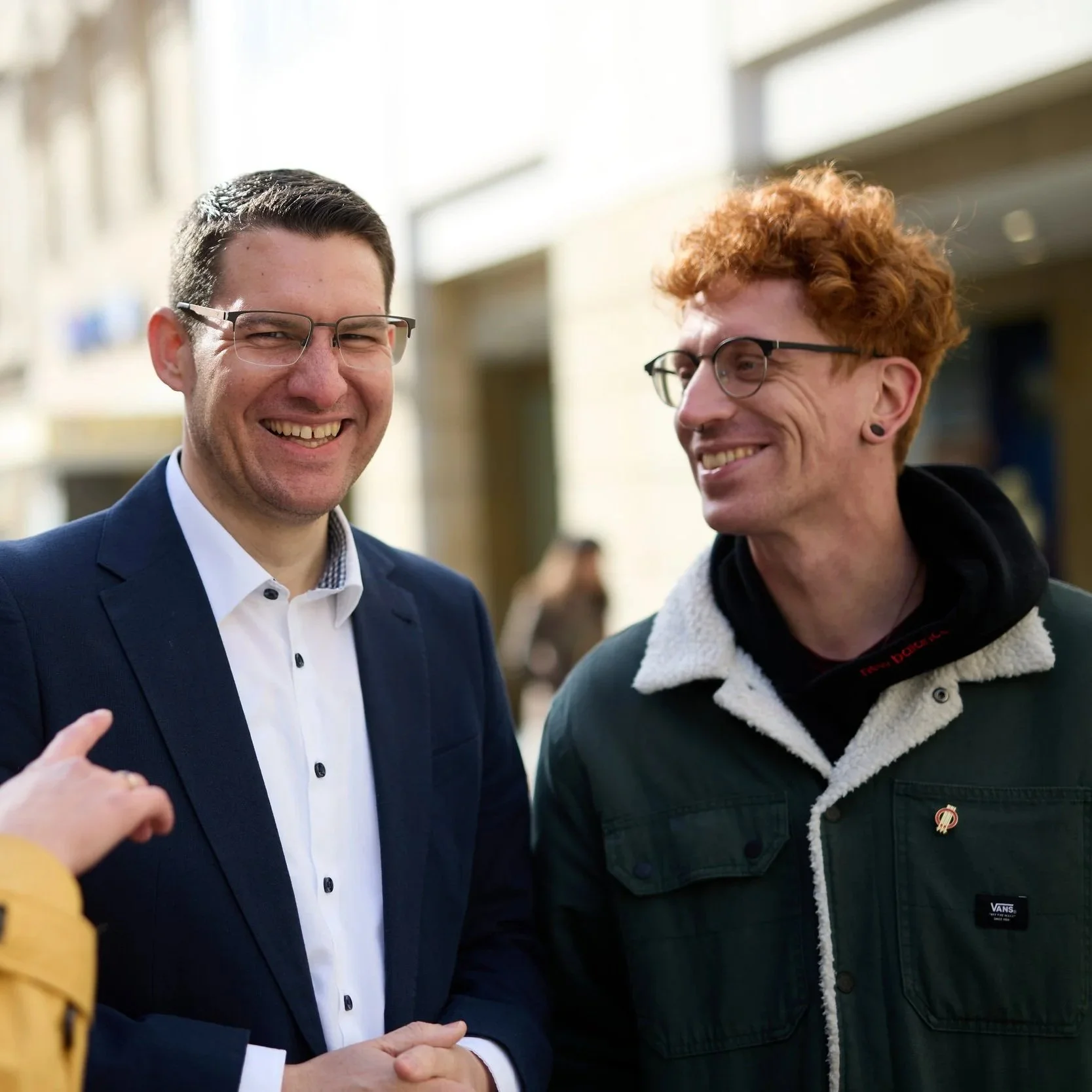 Zwei Männer stehen draußen gemeinsam, lachen und unterhalten sich.