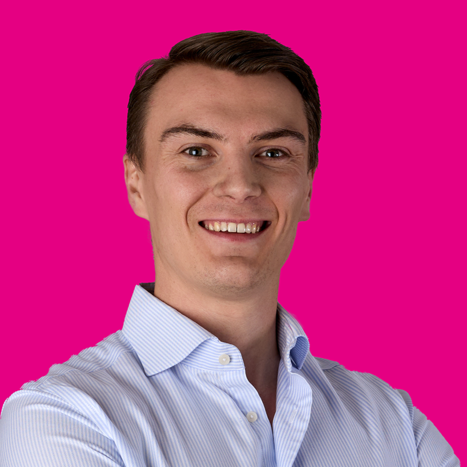 Porträt eines lächelnden jungen Mannes in Hemd vor pinkem Hintergrund.