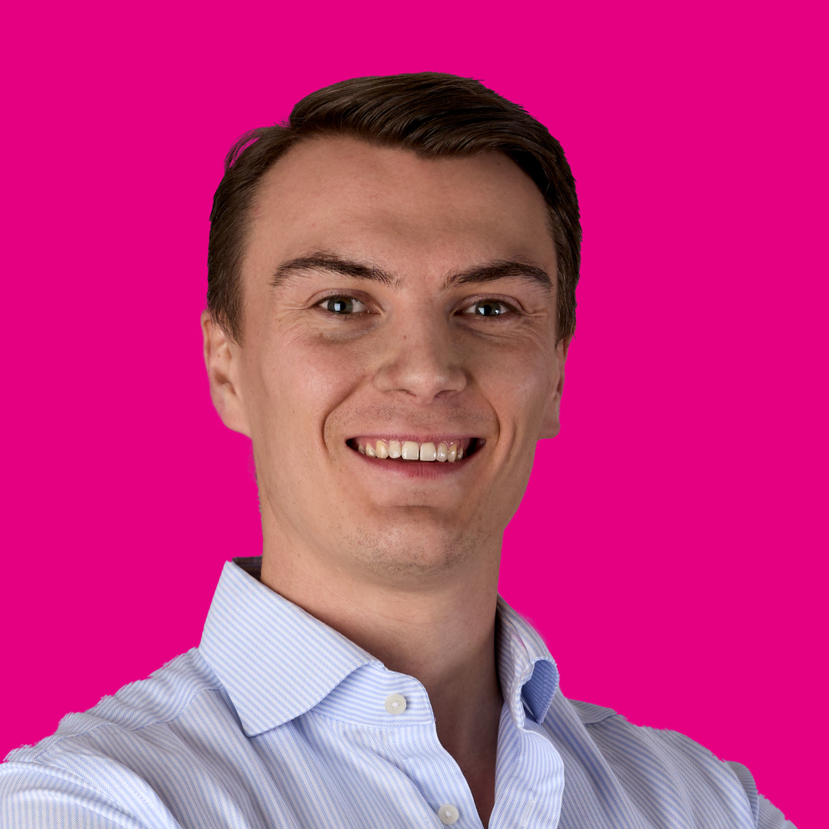 Junger Mann mit braunen Haaren, weißem Hemd, lächelnd vor pinkem Hintergrund.