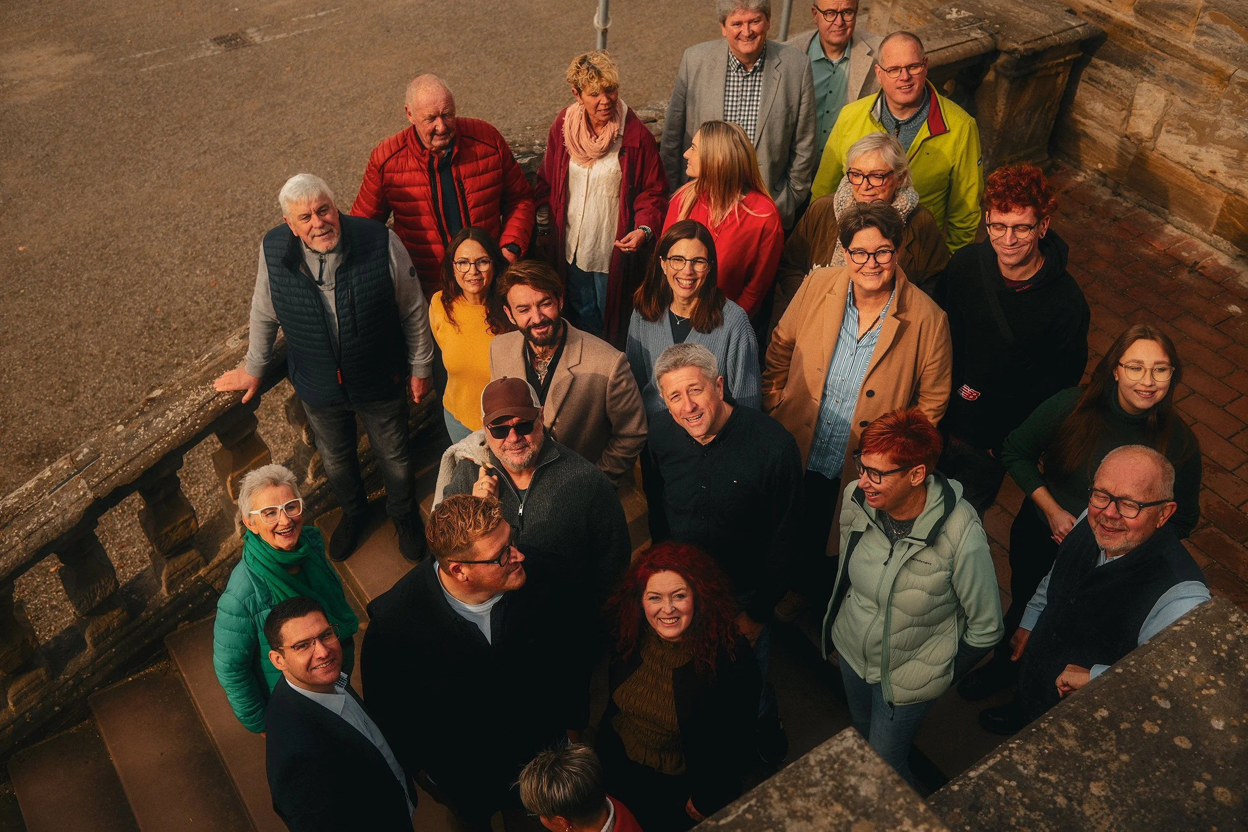Menschenmenge, die sich auf einer Treppe vor einer historischen Steinmauer versammelt hat.
