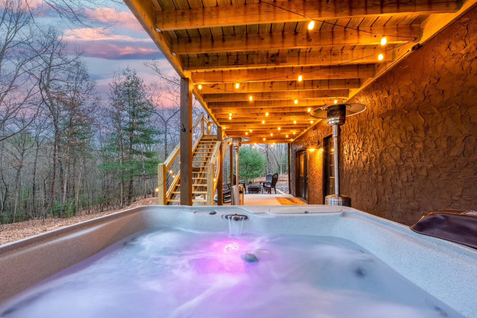 The outdoor hot tub at The Wizard Hideout surrounded by forest and private seating areas