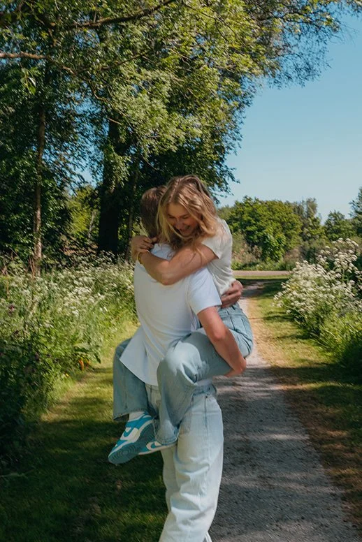 Vriend tilt vriendin op lachend lopen ze op een zonnig bospad – koppel fotografie