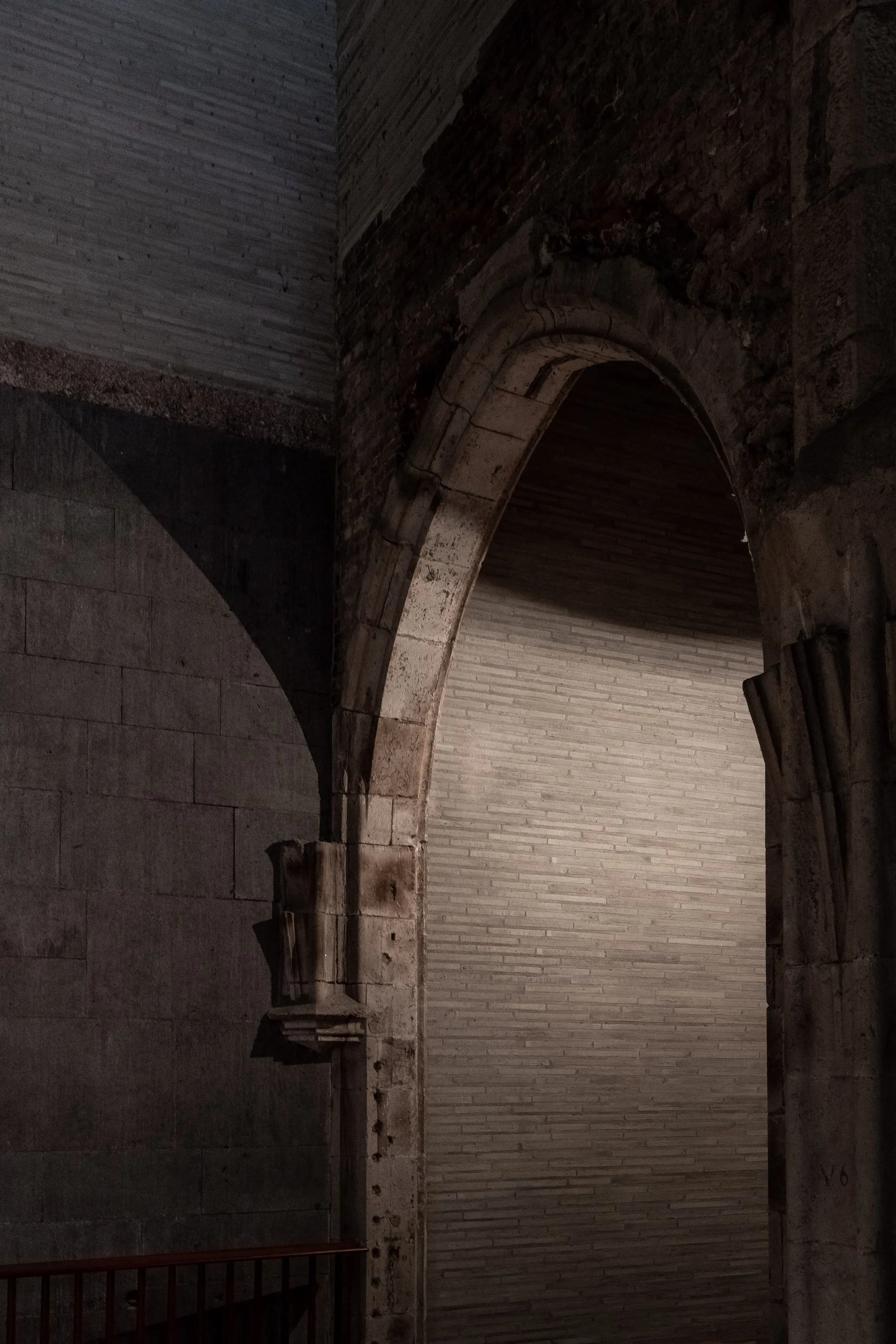Ein alter, historischer Architekturbogen aus Stein und Ziegeln, teilweise in dunklem Licht.