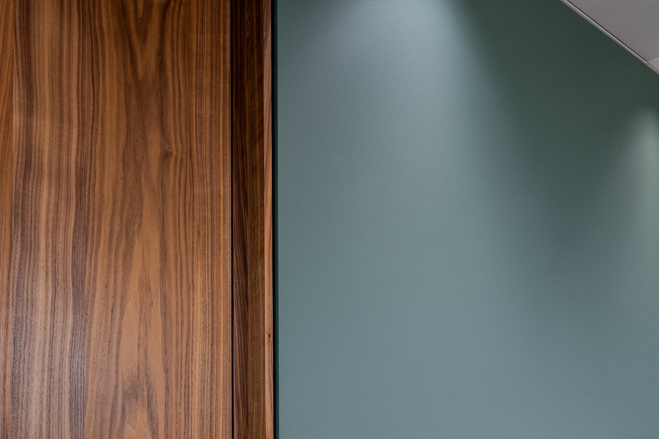 Nahaufnahme von einer Wand mit Holzpaneelen und einer grünen Wand neben einer Decke mit Metallrand.