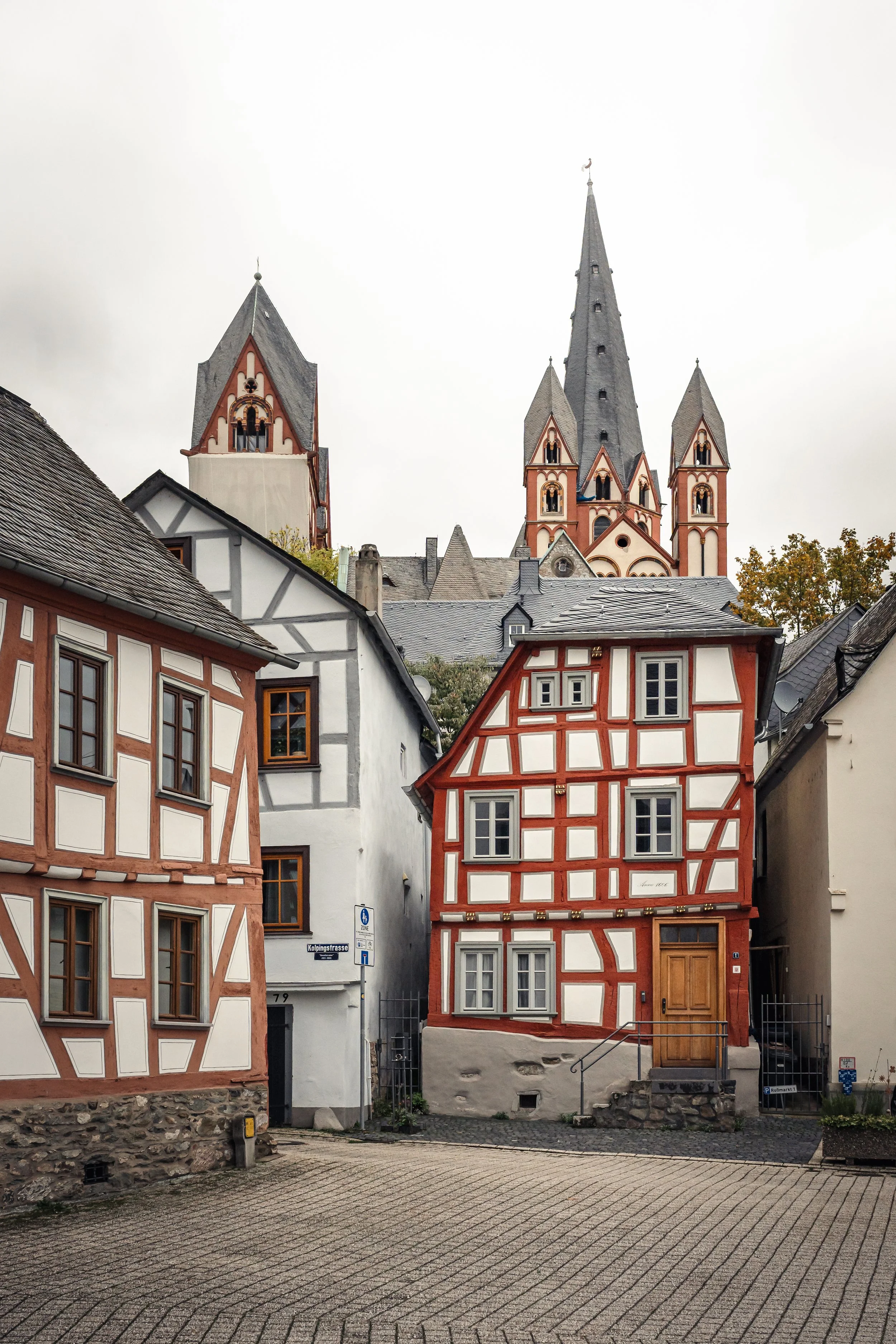 Historische Fachwerkhäuser vor einer gotischen Kirche in einer kleinen Stadt, im Herbst mit nebligem Himmel.