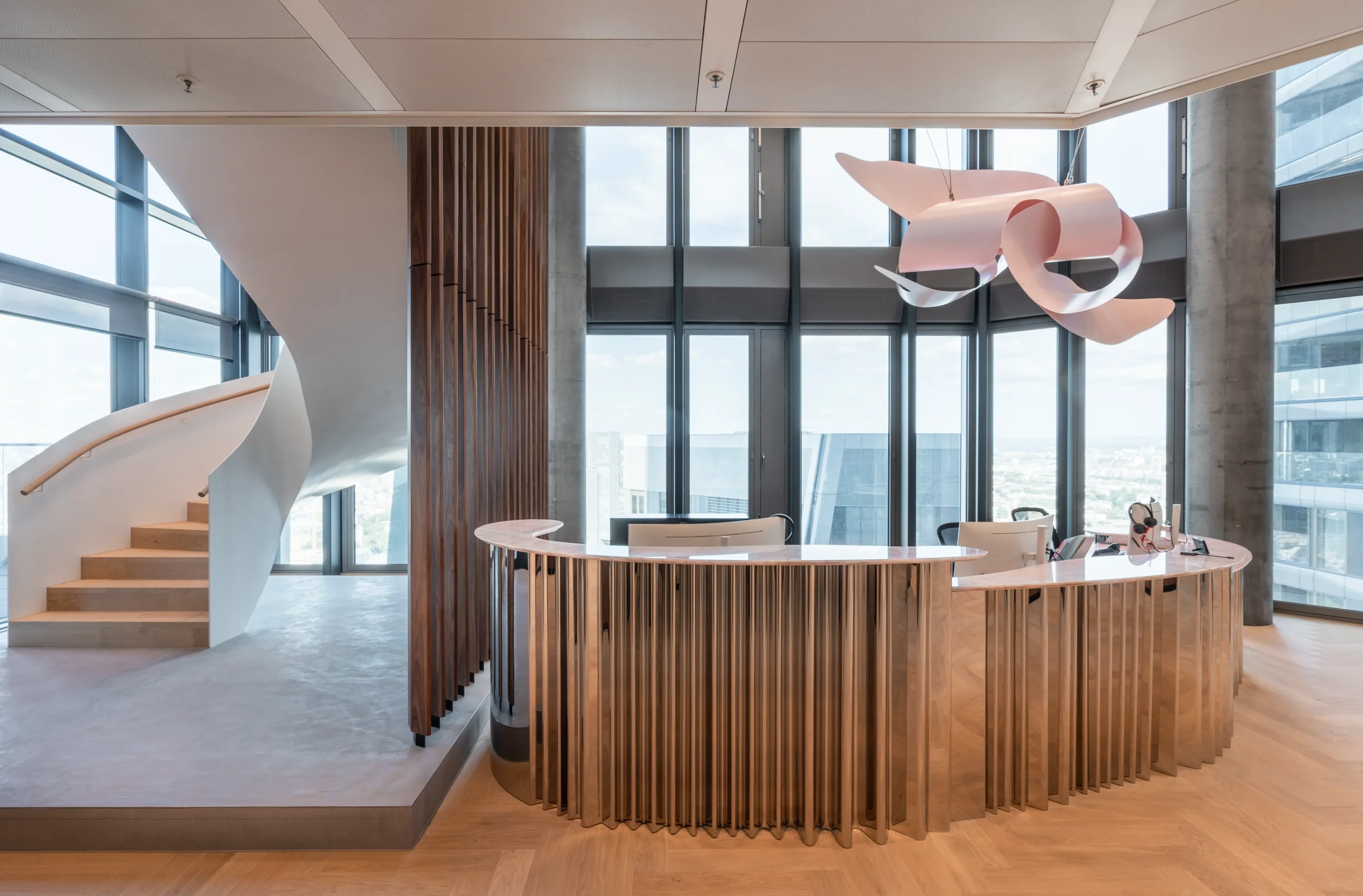 moderne Empfangstheke in einem hellen, urbanen Büro mit großen Fenstern, Holz- und Stahlelementen, und einer skulpturalen Lampe