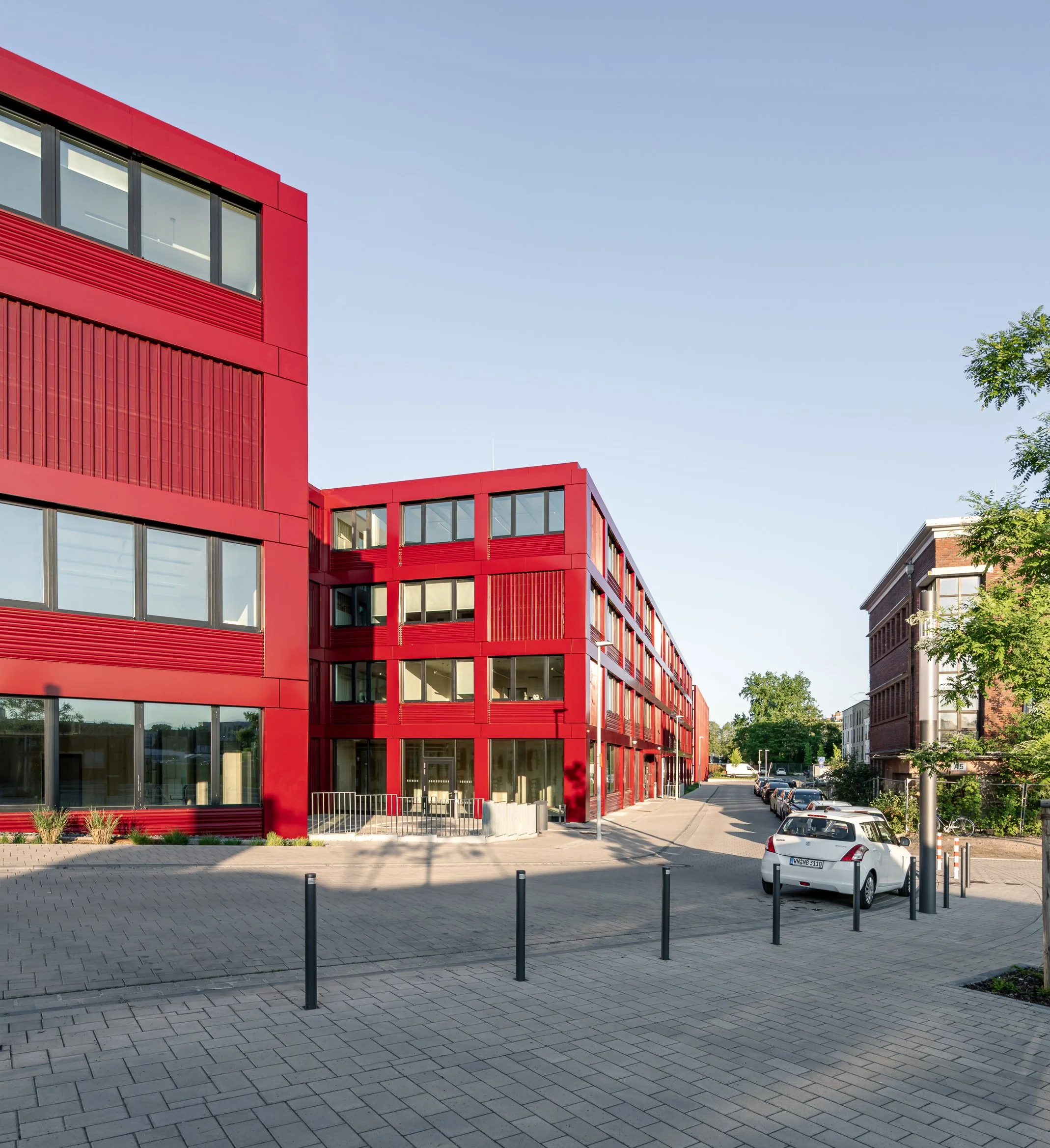 Fluchtperspektive eines modernen Bürobau mit roter Fassadenverkleidung bei goldener Stunde in Bonn