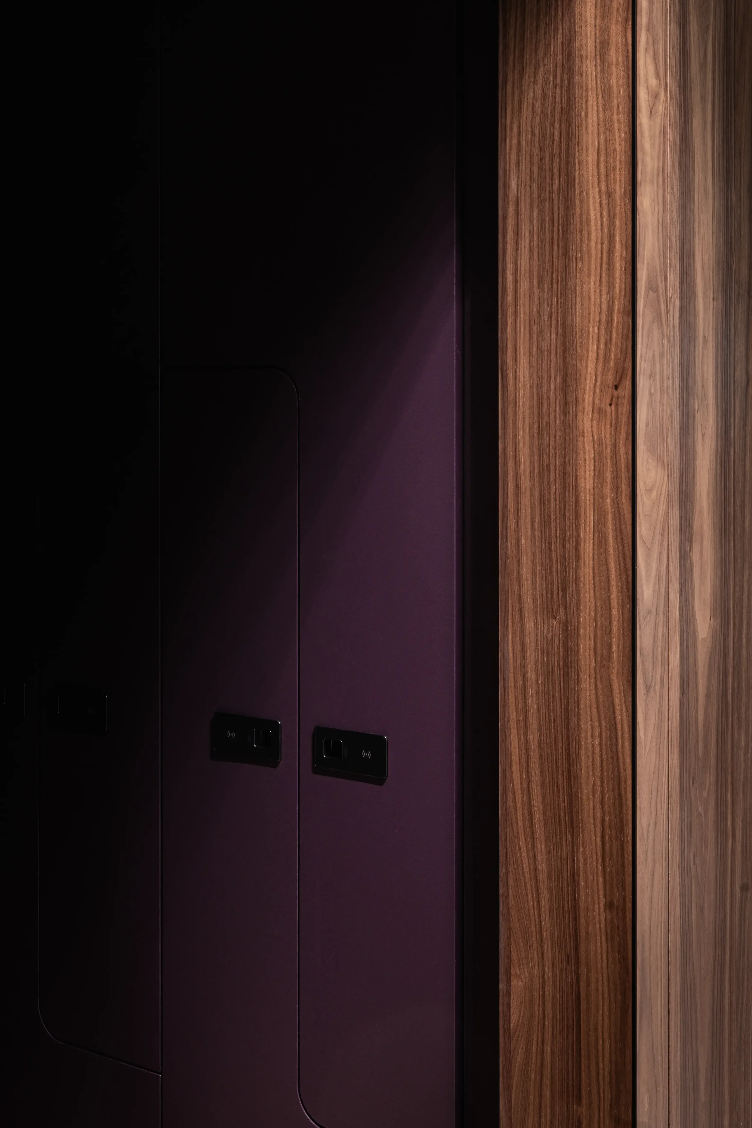 Nahaufnahme eines modernen, dunklen Schranks mit integrierten schwarzen Steckdosen, neben einer Holzoberfläche.